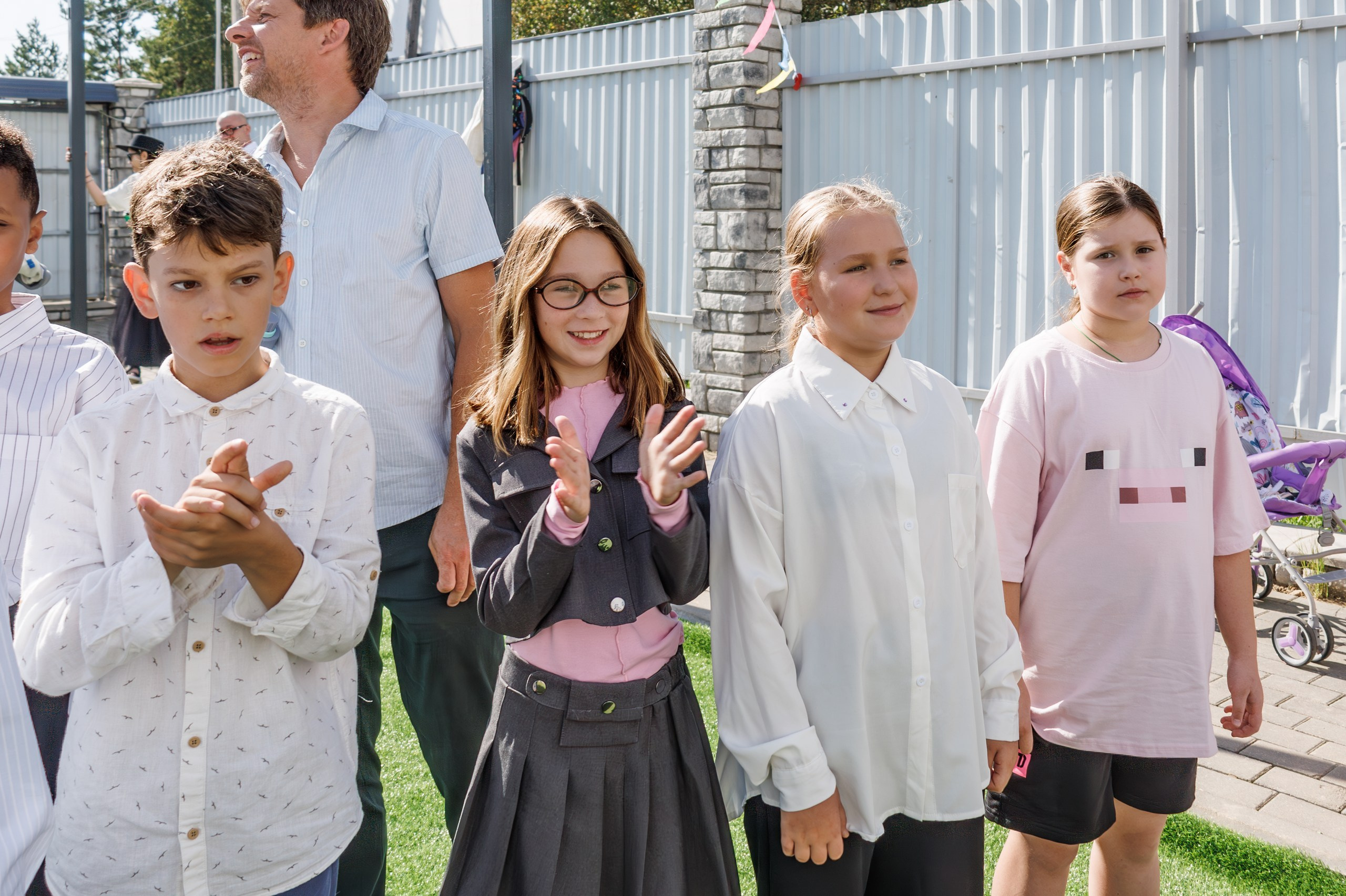 Линейка 1 сентября в школе - дети с букетами, радостные родители и учителя; дети обнимаются, радуются встрече с друзьями после каникул