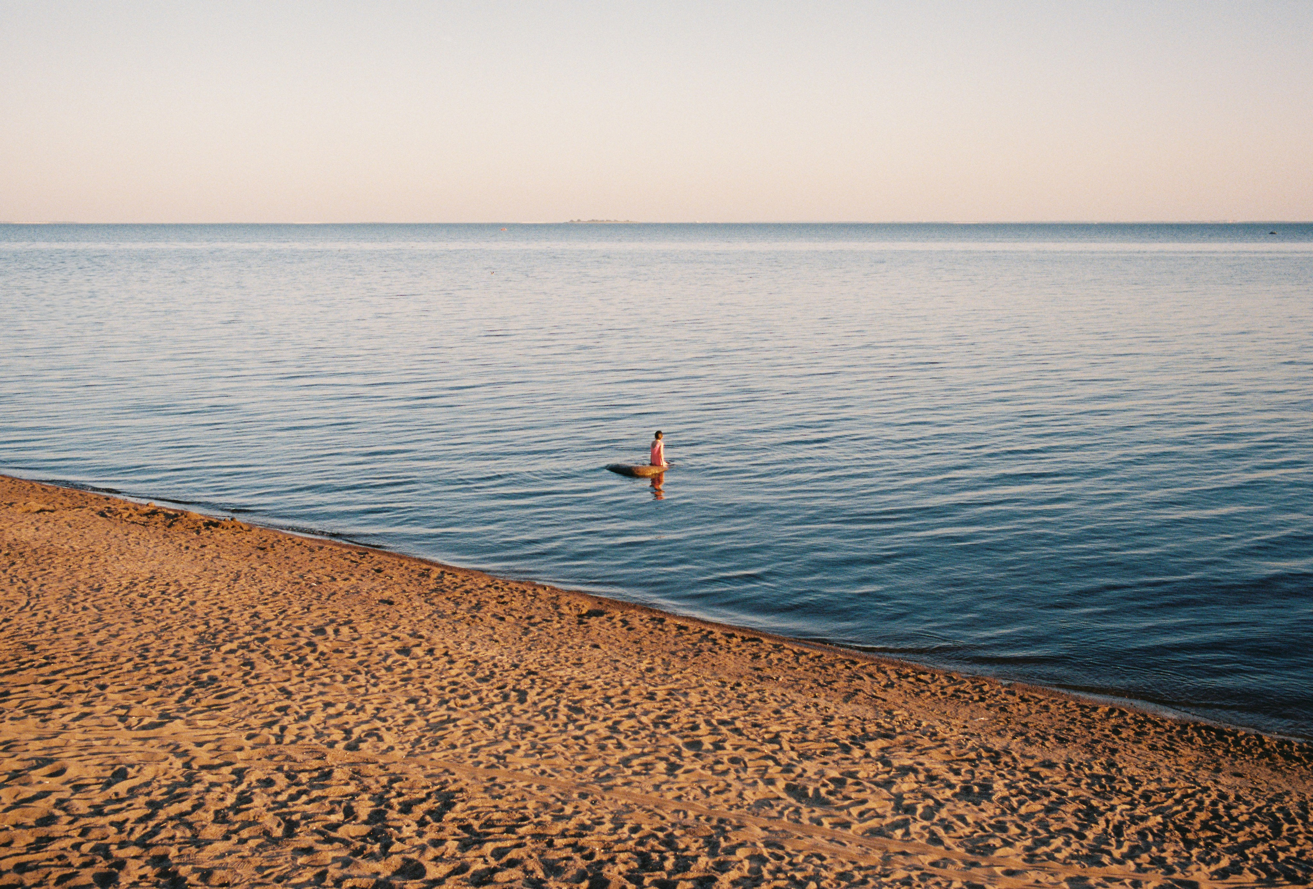 Купальщица сидит на камне в воде в Финском заливе