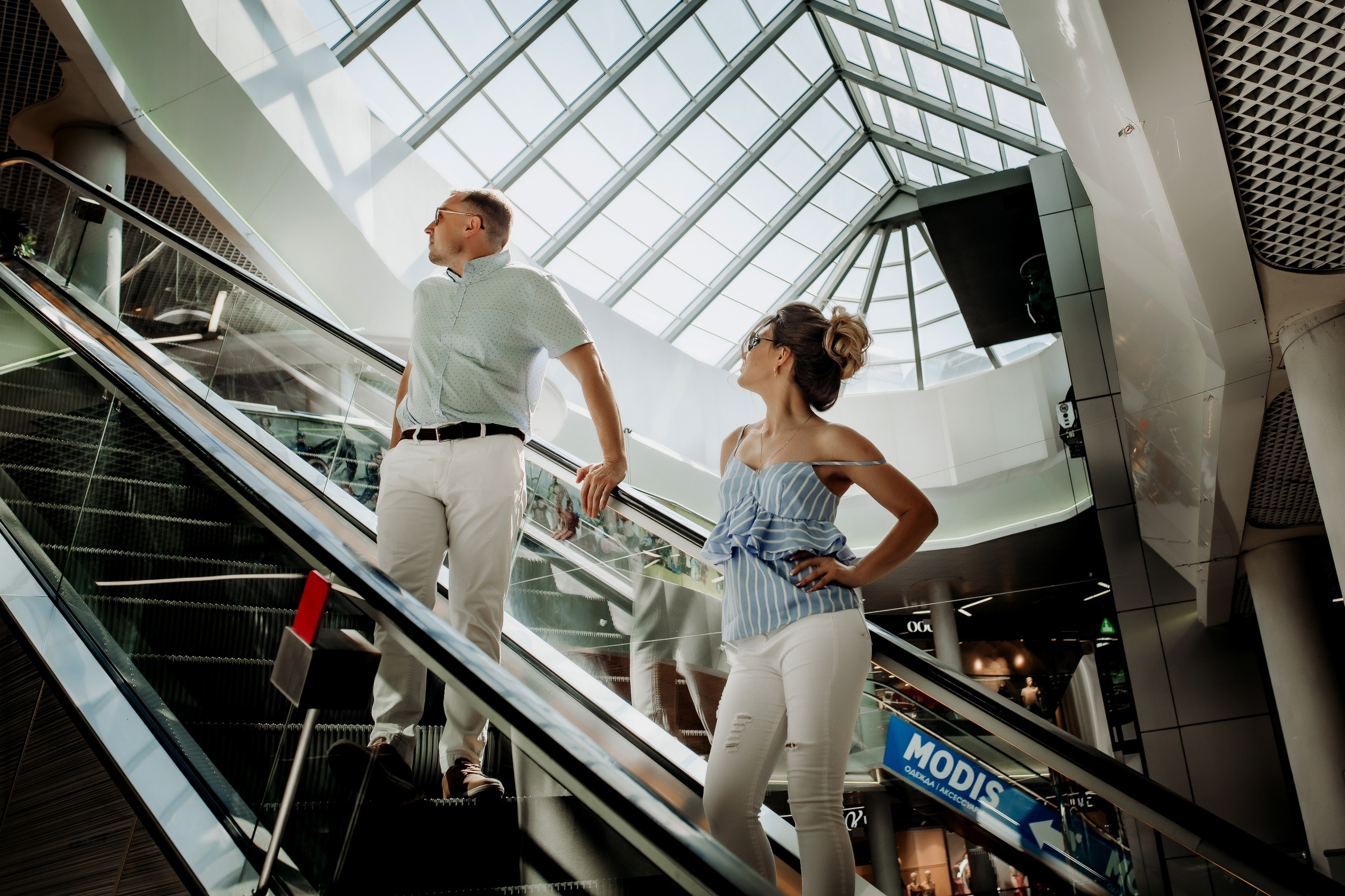 Парень и девушка едут на эскалаторе в торговом центре Смоленска 