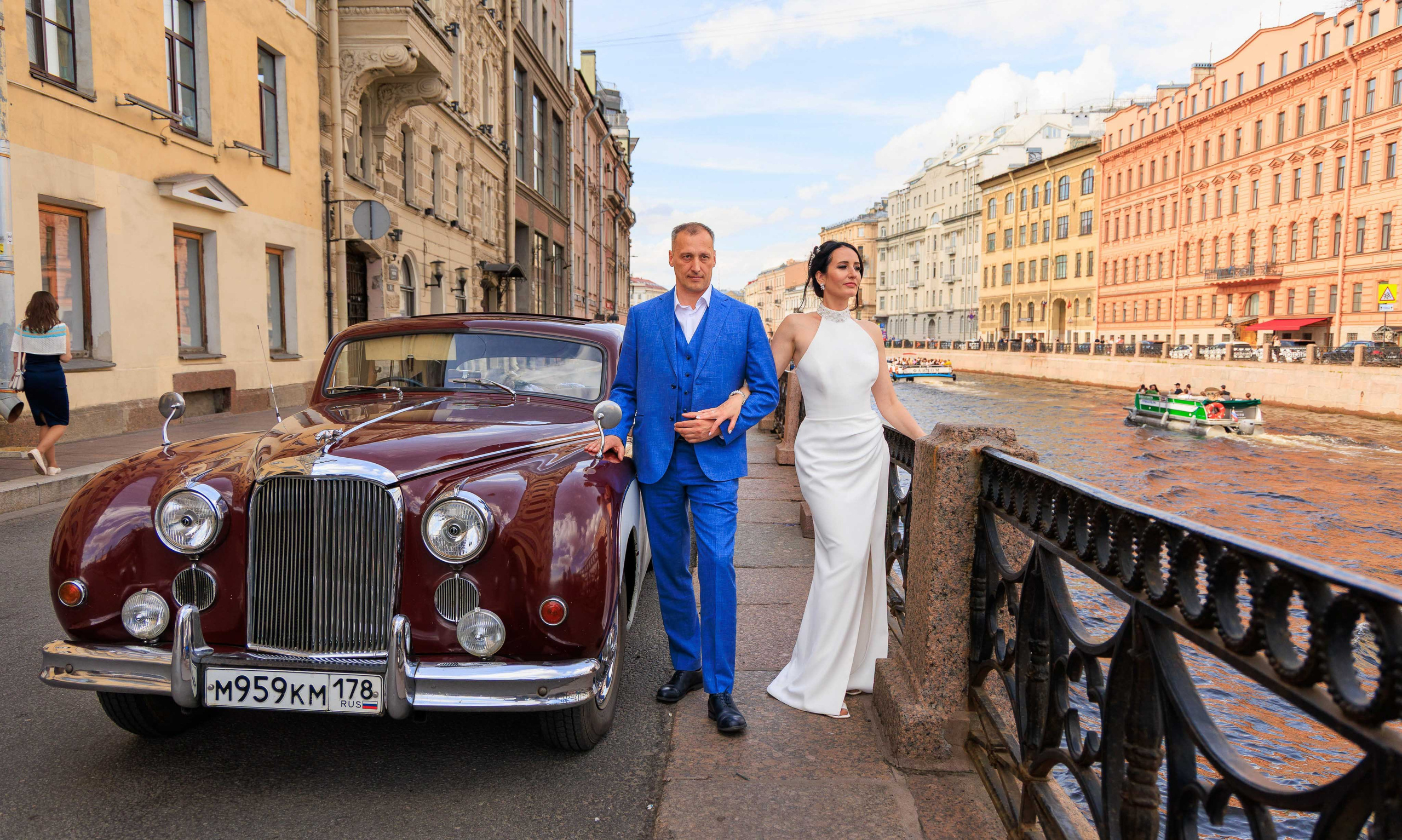 Жених и невеста гуляют, держась за руки, по набережной Невы.