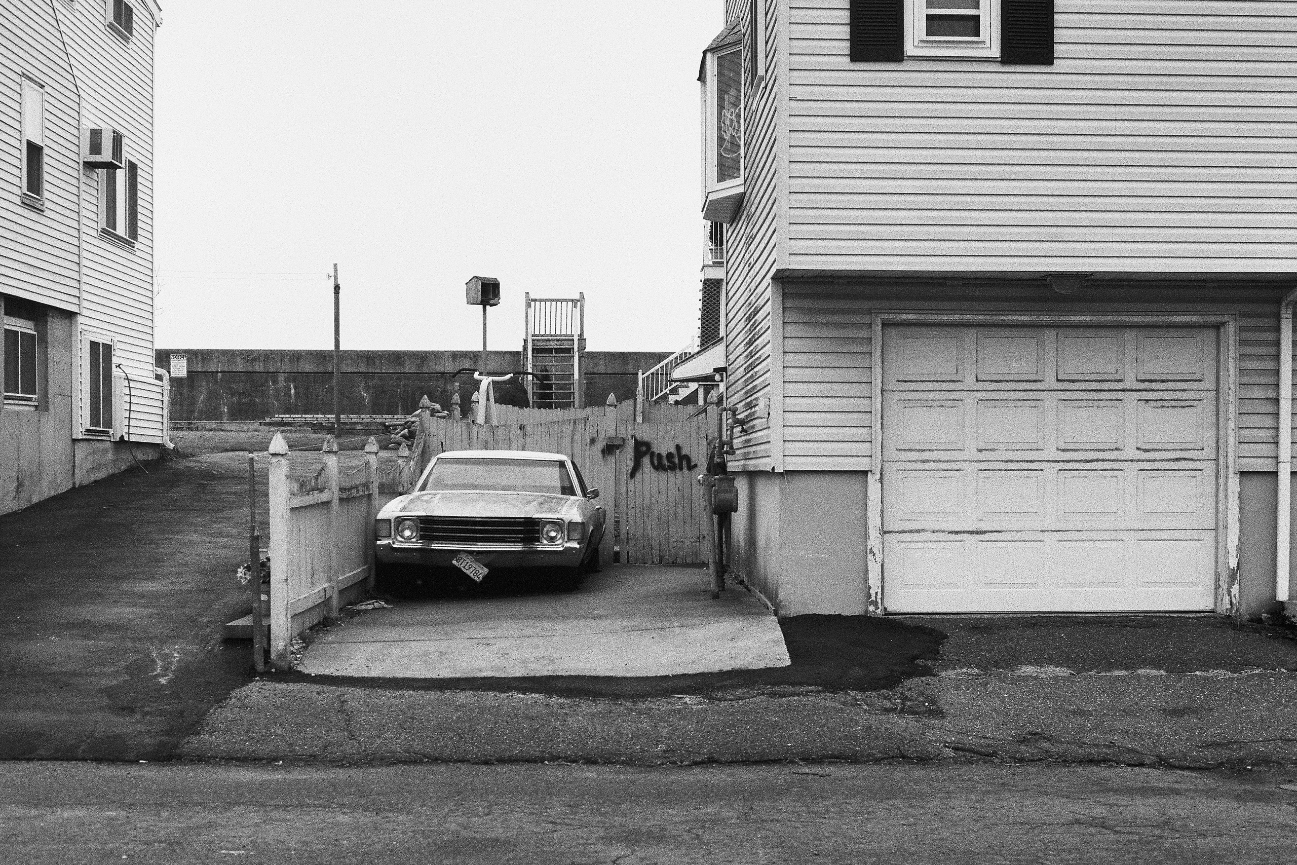 черно-белый городской пейзаж спального района Бостона, США. Ретро автомобиль во дворе дома.