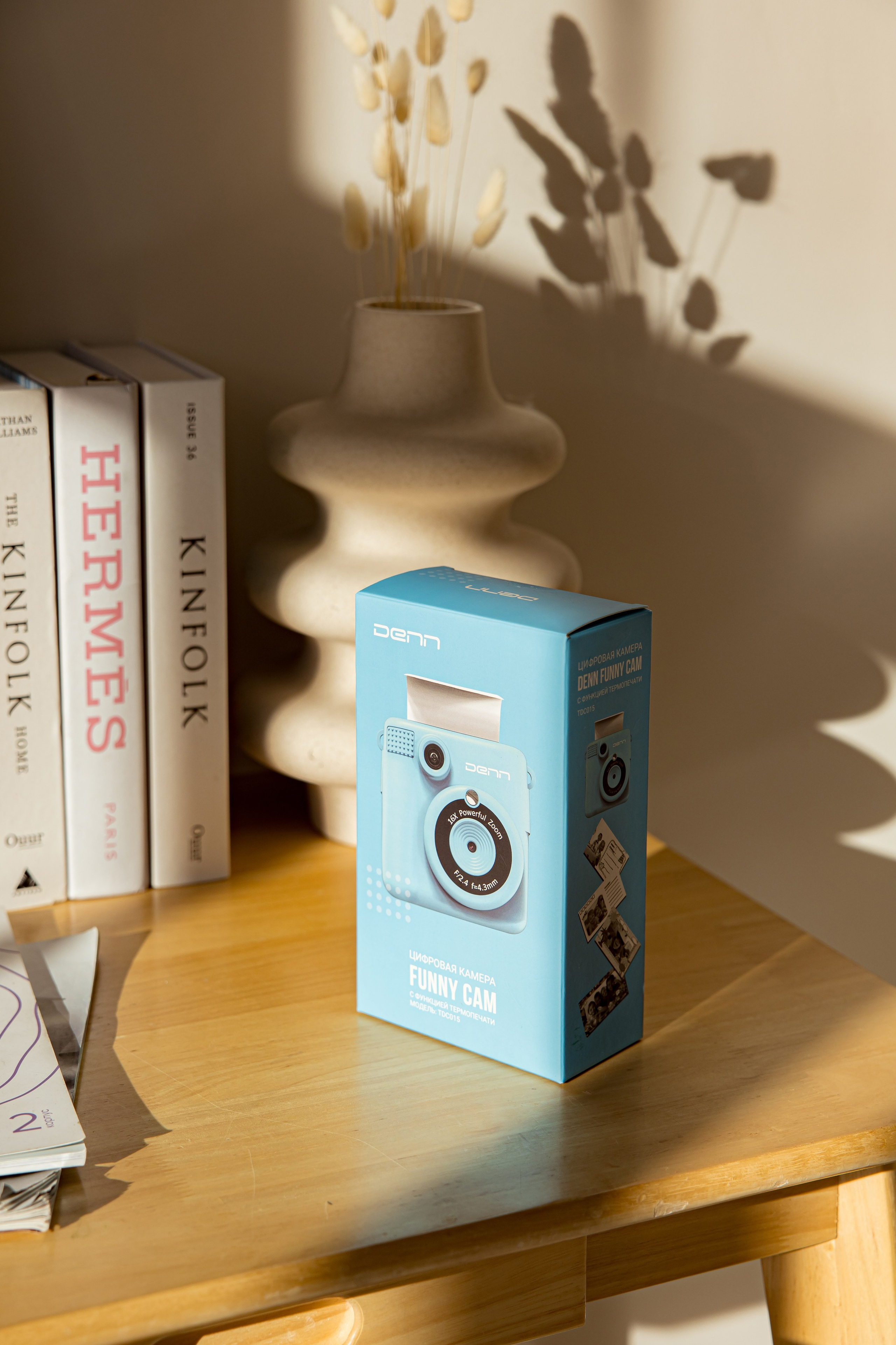 Коробка с камерой моментальной печати стоит на столе на солнце