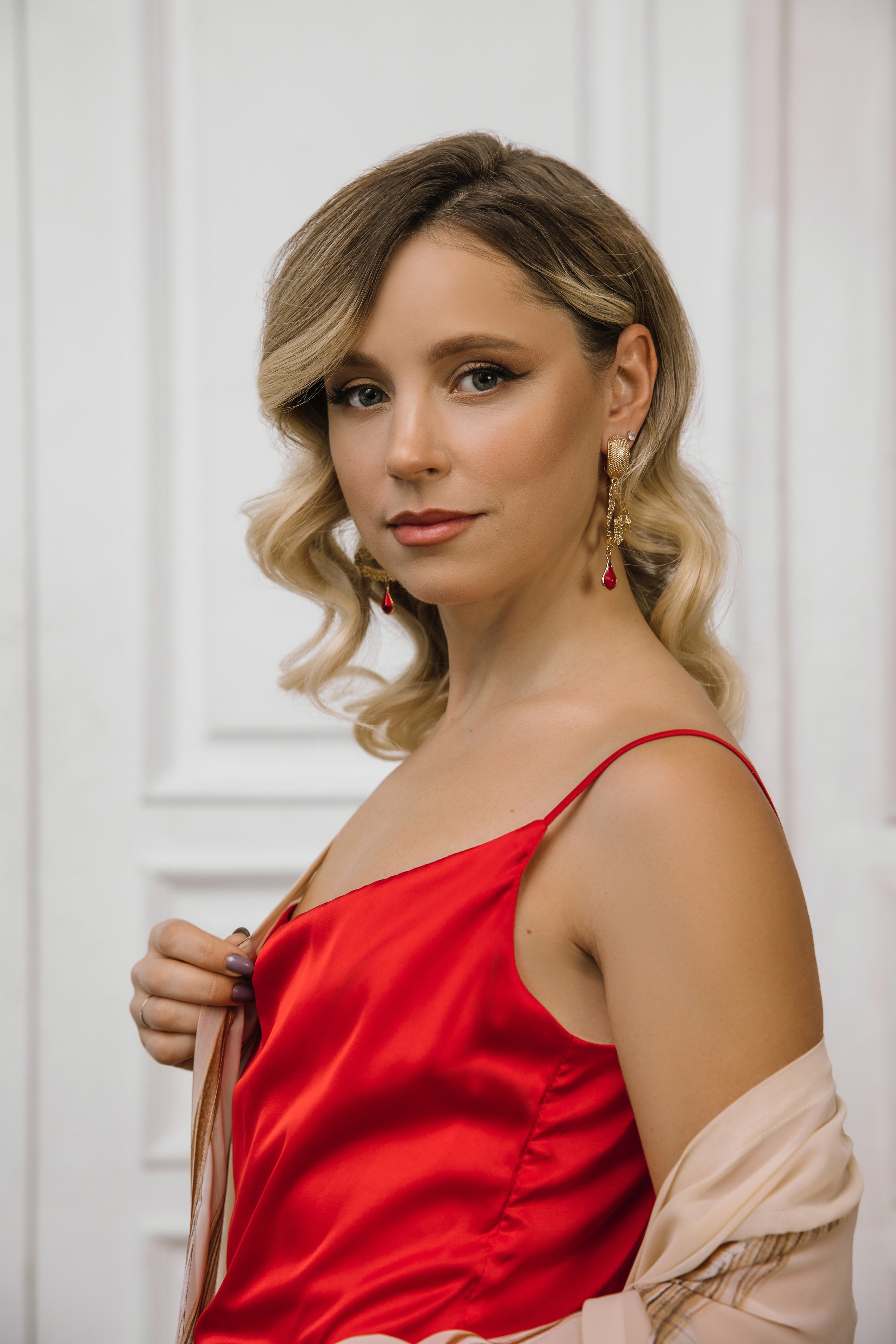 Девушка в красном шелковом платье комбинация сверху надета бежевая туника.