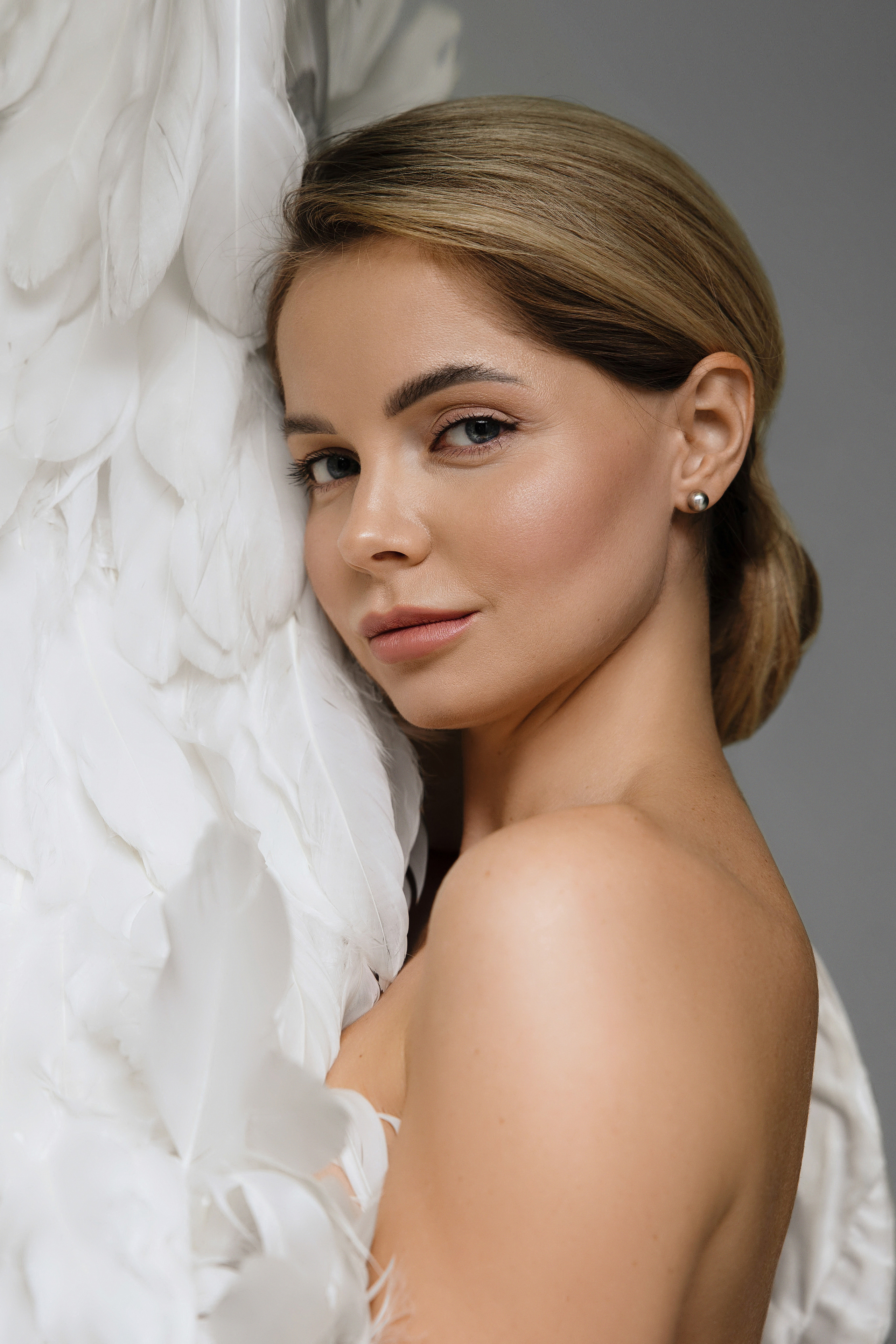 Портрет беременной блондинки в белой накидке из перьев.