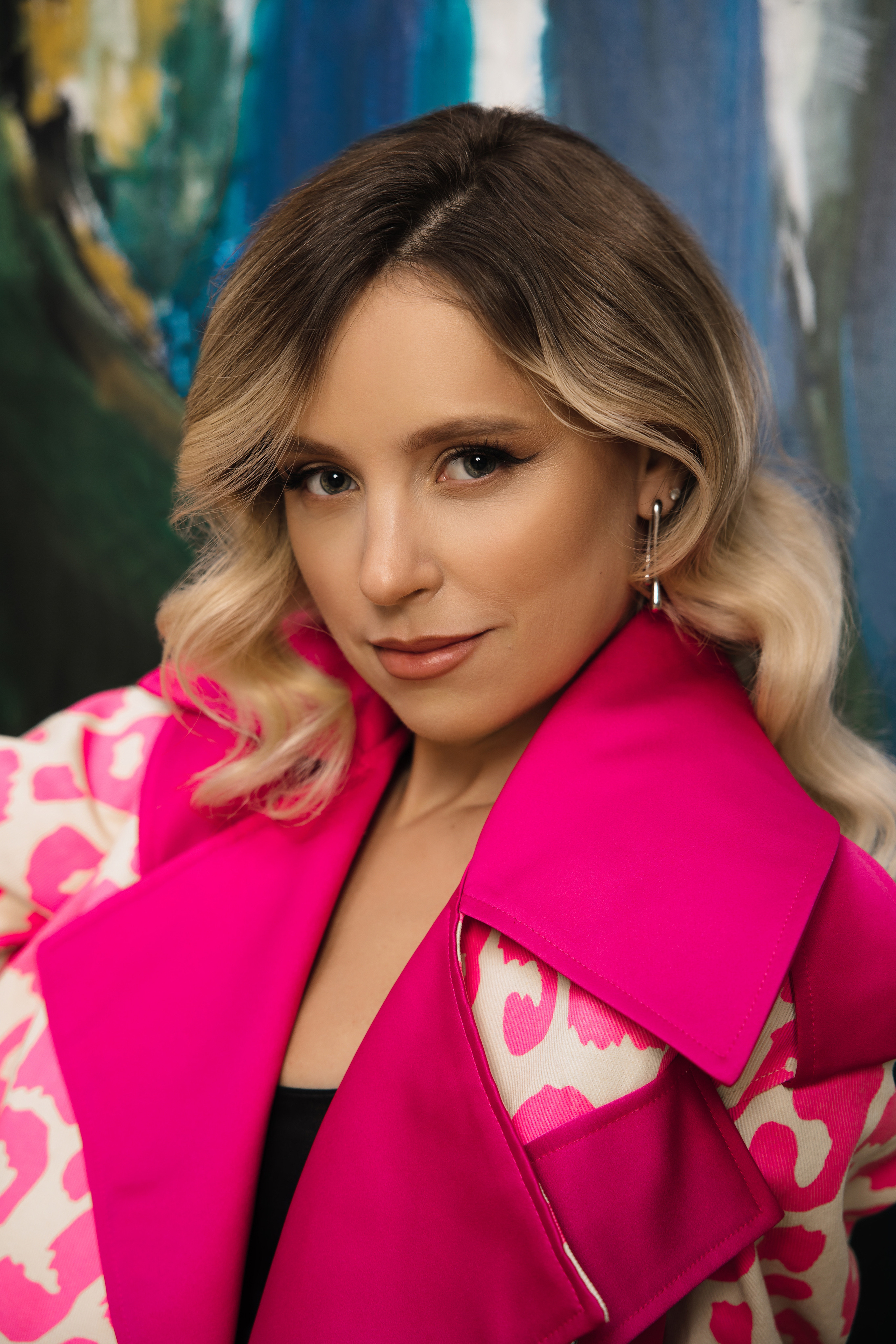 Яркая девушка блондинка в кожаной куртке цвета фуксия.