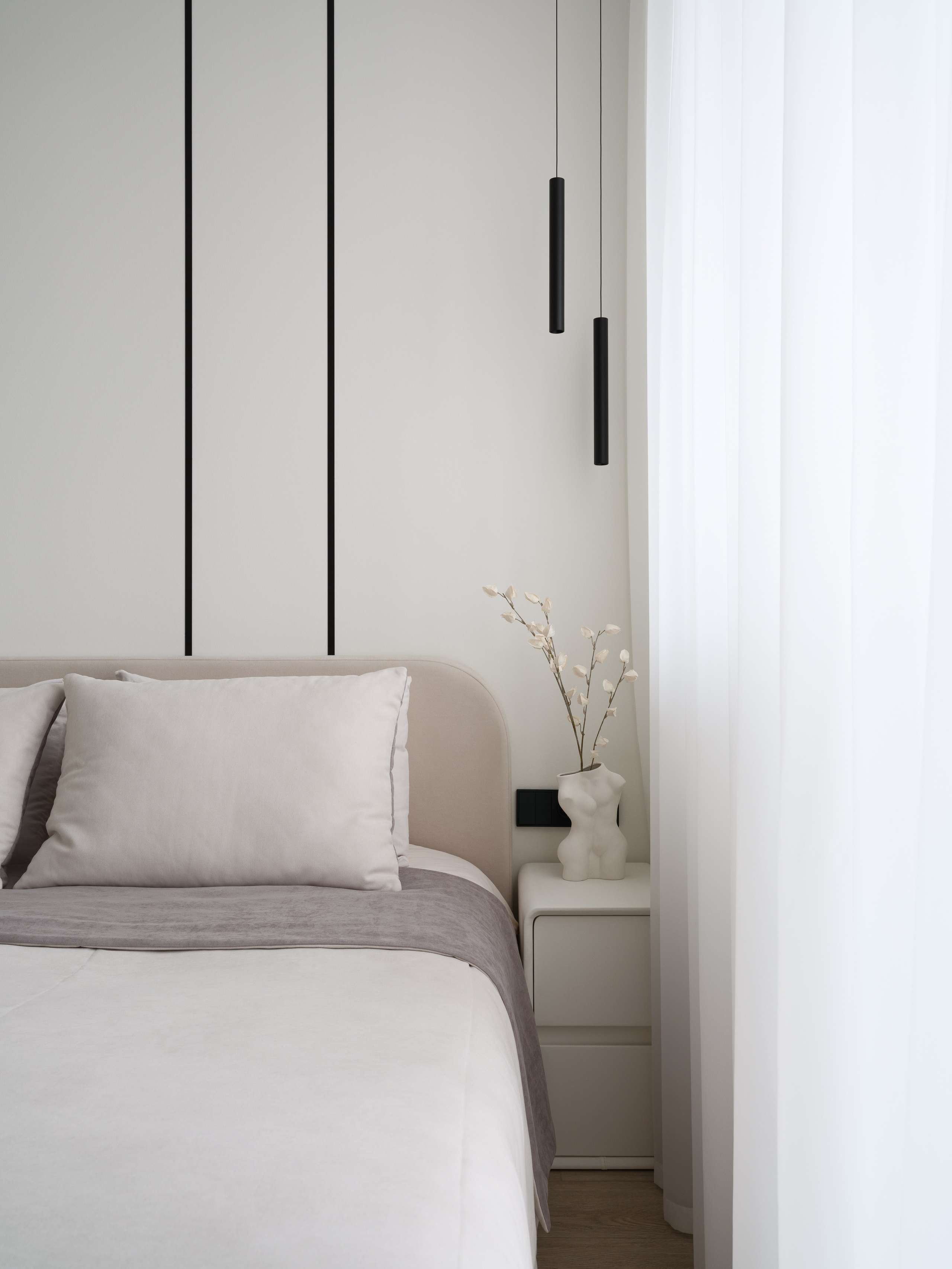 Современный минималистичный интерьер спальни: кровать с нейтральным текстилем, прикроватная тумба с дизайнерской вазой и подвесными светильниками. Автор проекта — дизайнеры Евгения Княжева и Владлена Привалова, фотограф Сергей Денисенко