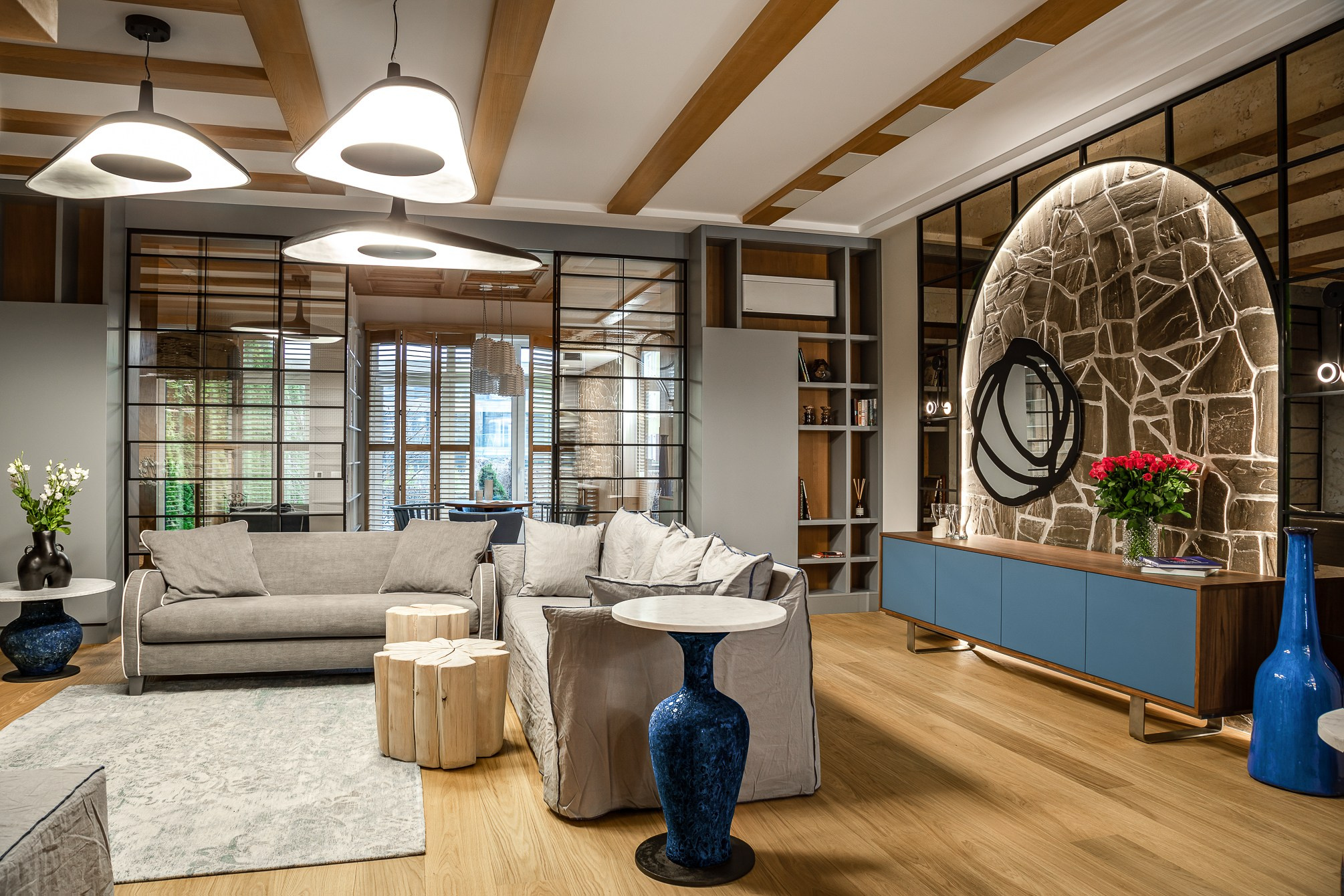 Гостиная с бежевым диваном, синими тумбами и вазами.