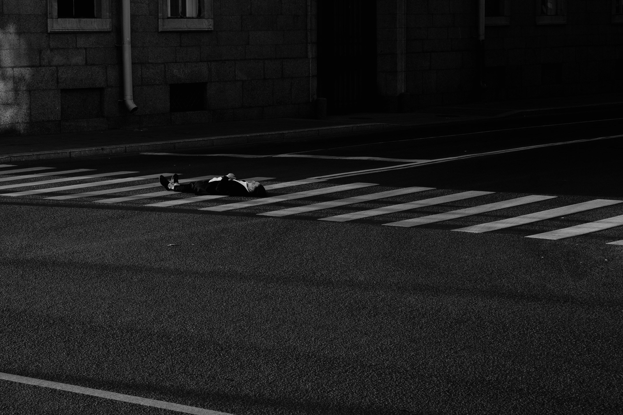 Снимок лежащего молодого человека на пешеходном переходе 