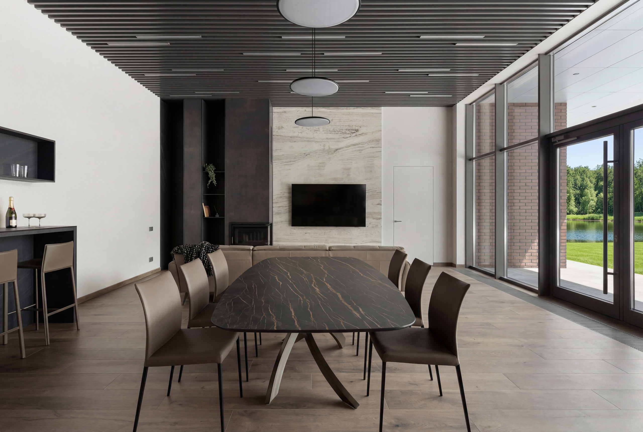 Интерьер столовой и гостиной от Валерии Котович: обеденный стол с каменной столешницей, панорамное остекление с видом на озеро, реечный потолок и акцентная стена из травертина в доме у воды.