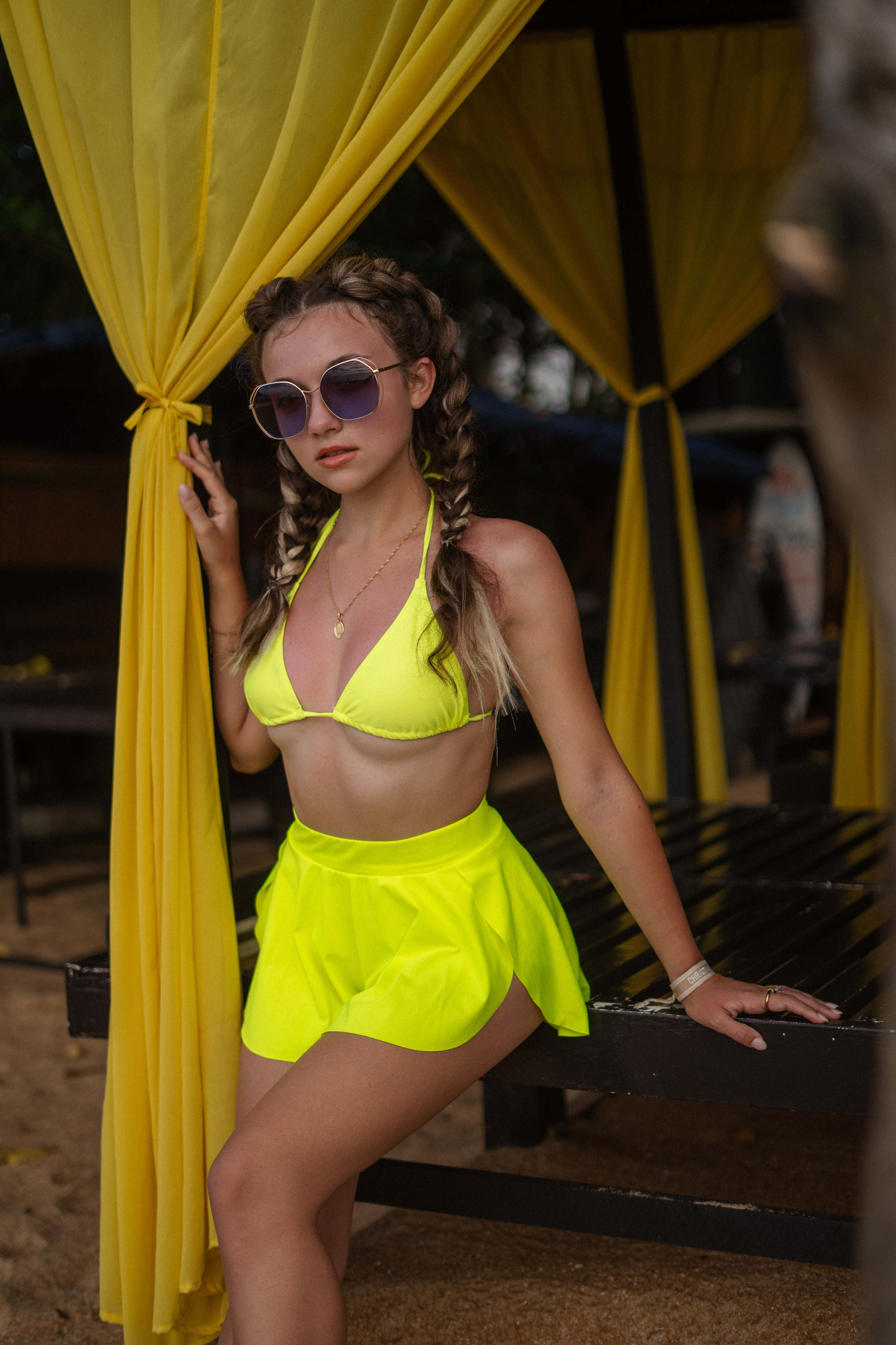a girl with braids in a yellow swimsuit taking steps along the ocean shore