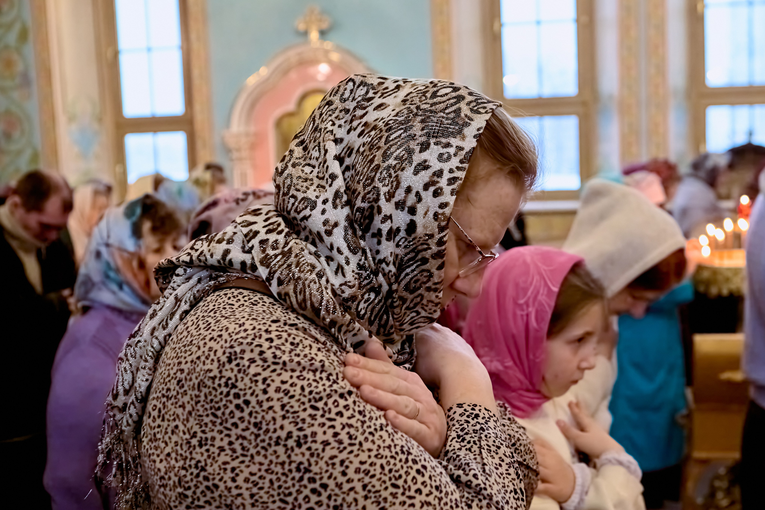 Женщина Мама с дочкой стоят со сложенными руками на Херувимской песни в храме