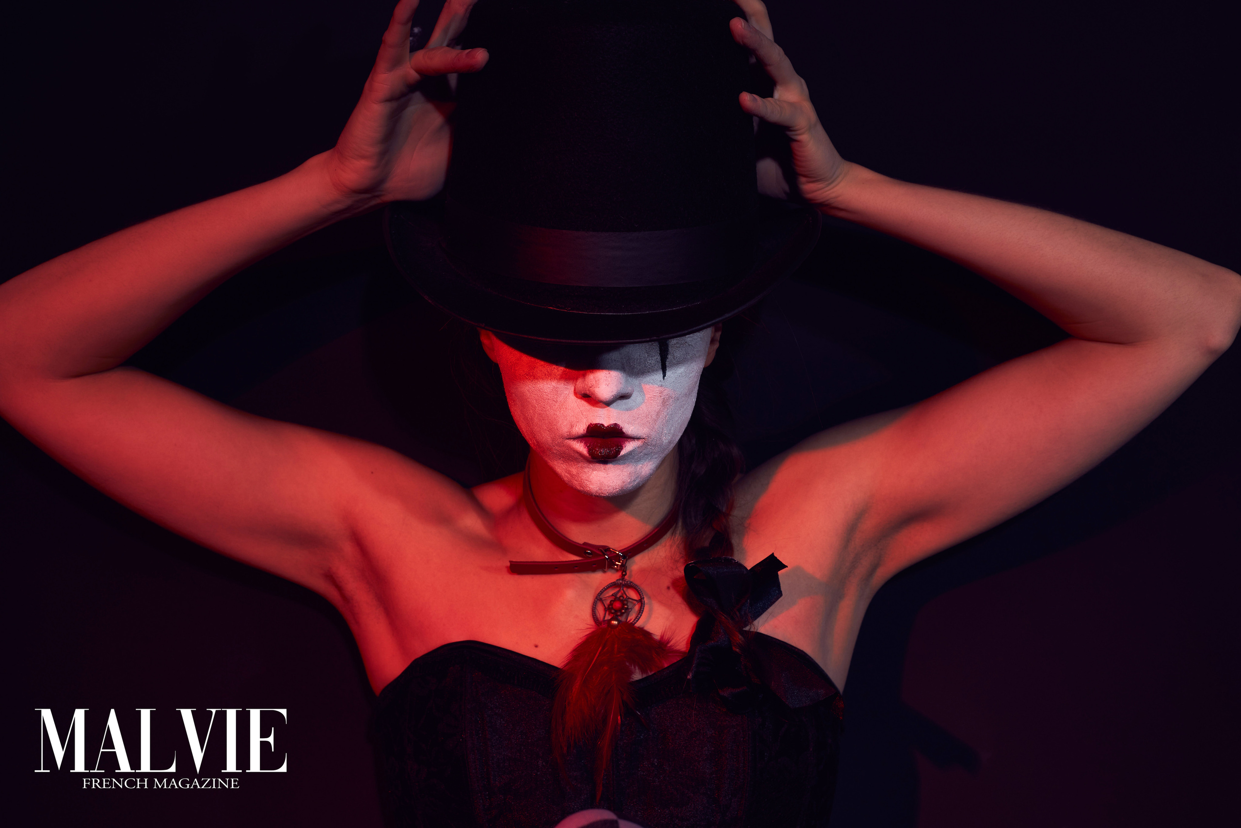 Портрет девушке в черном цилиндре  и корсете и с белым клоунским гримом на лице