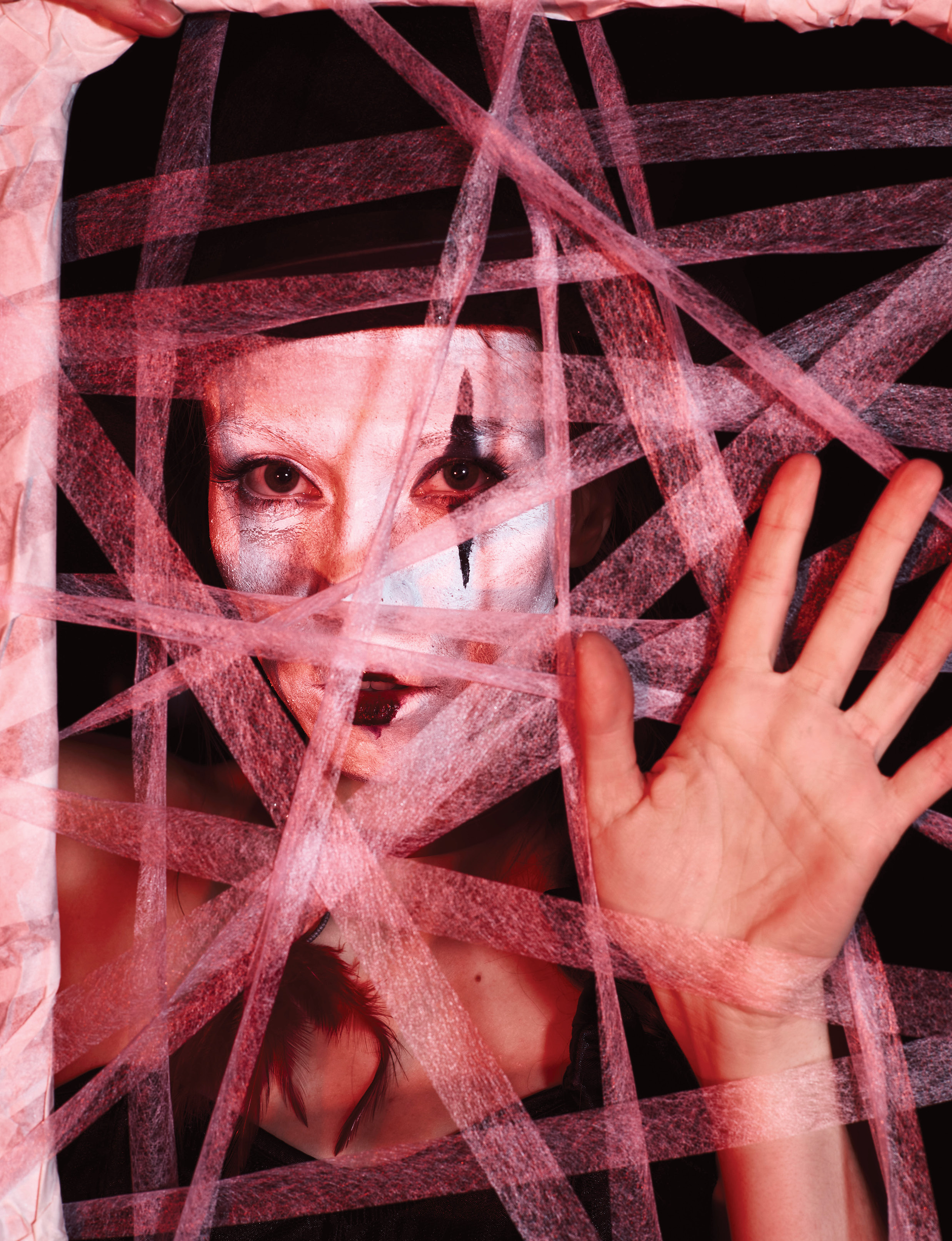 Клоунесса смотрит сквозь рамку картины с натянутыми на неё паутинками нитей