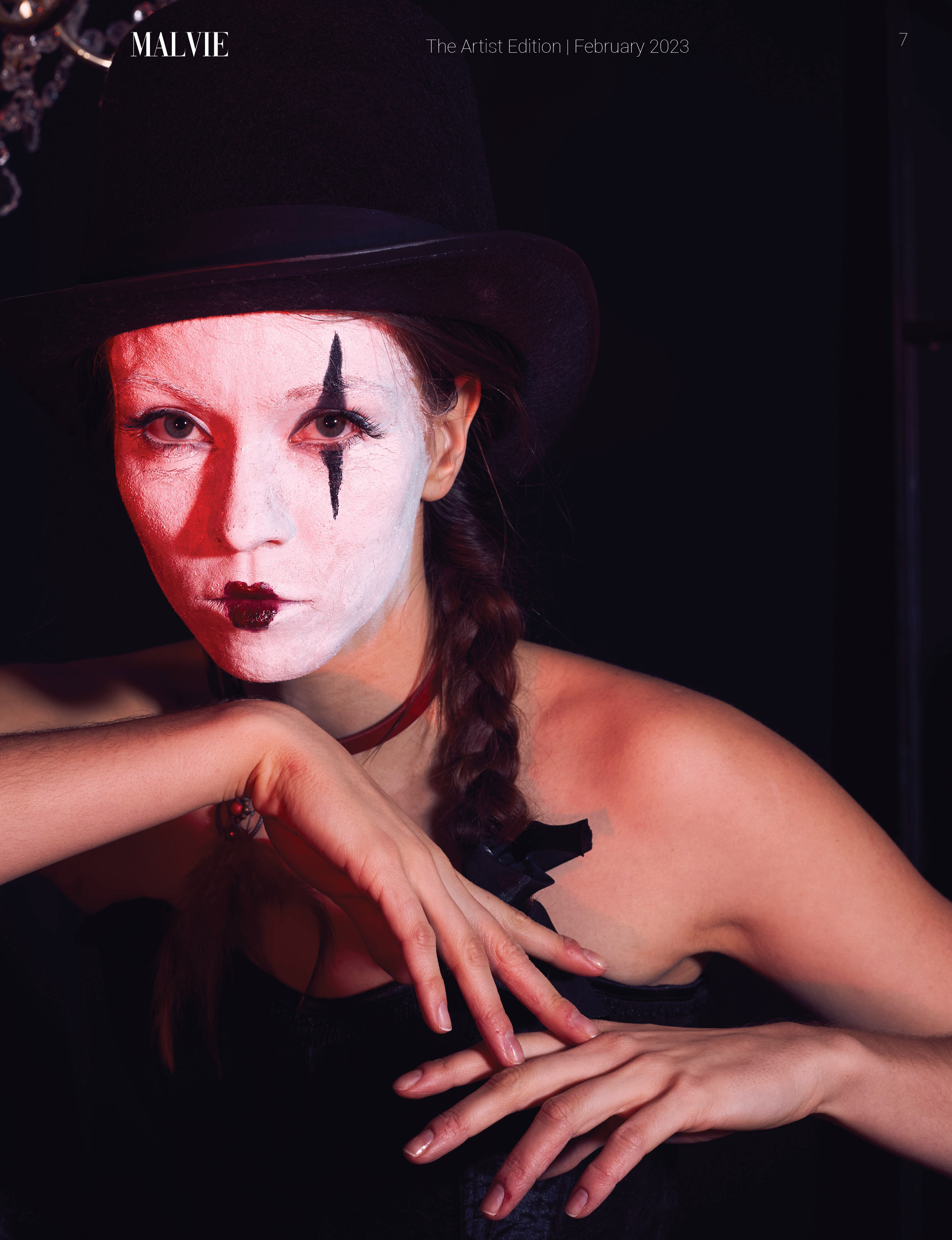 Крупный портрет клоунессы в цилиндре с белым гримом на лице