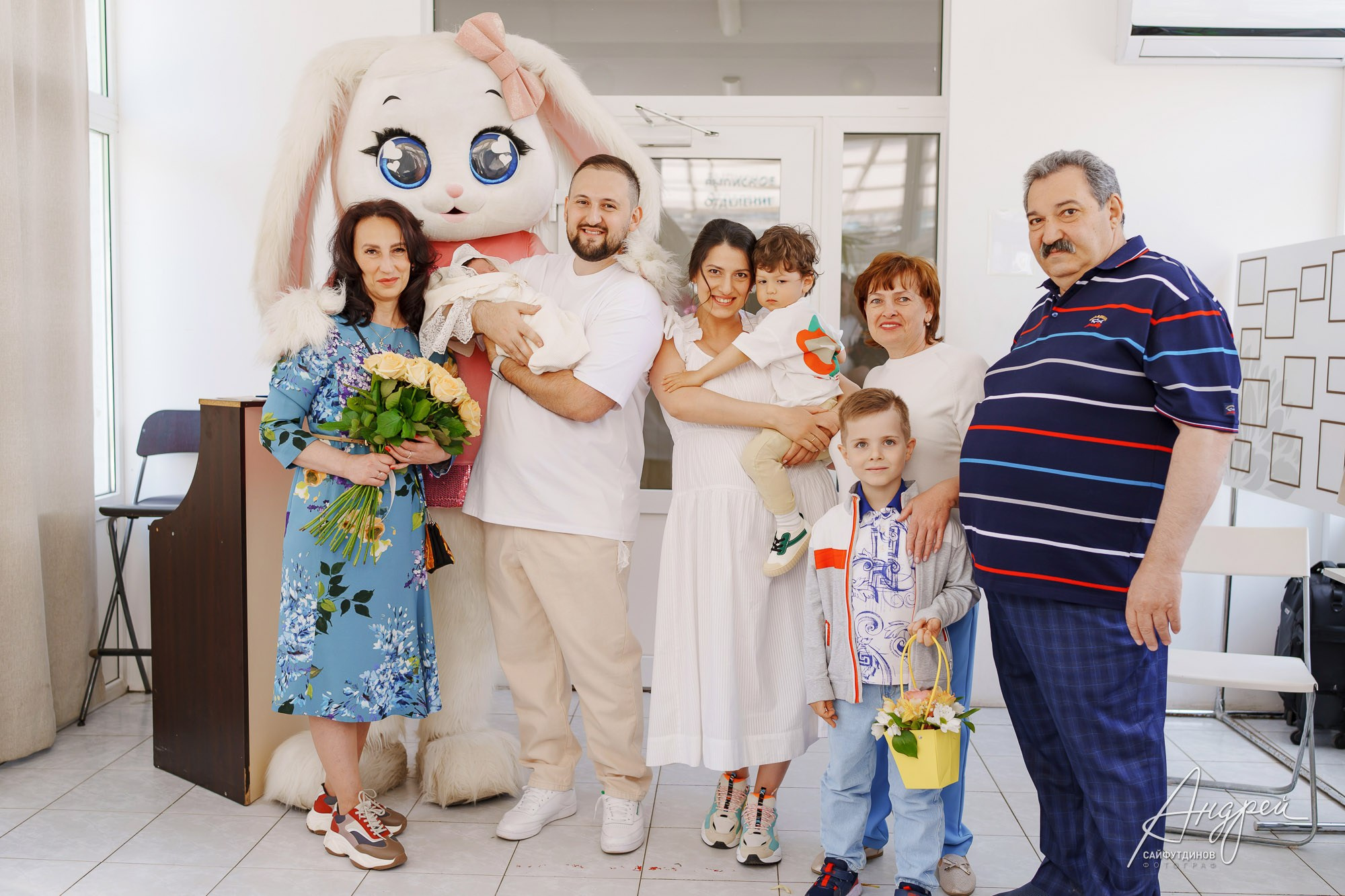 Молодые родители с новорожденной дочкой на фотозоне роддома ЦГБ в окружении гостей, Ростов-на-Дону, фотосъемка выписки.