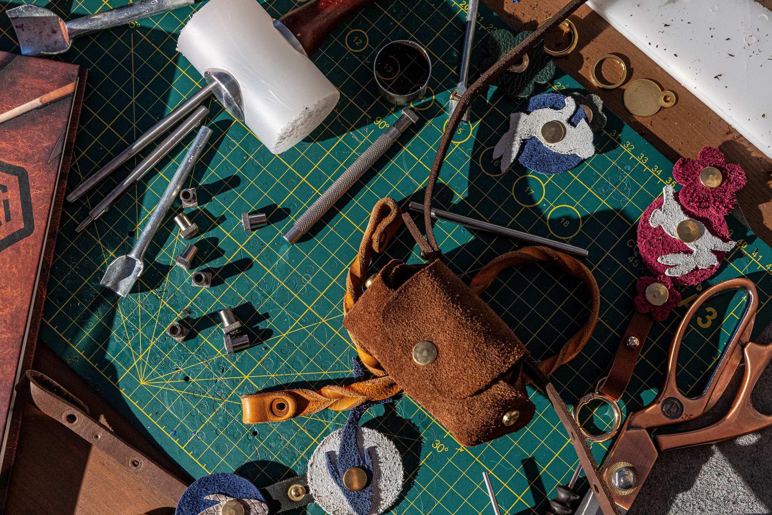 На рабочем столе — разложенные инструменты и заготовки из натуральной кожи.