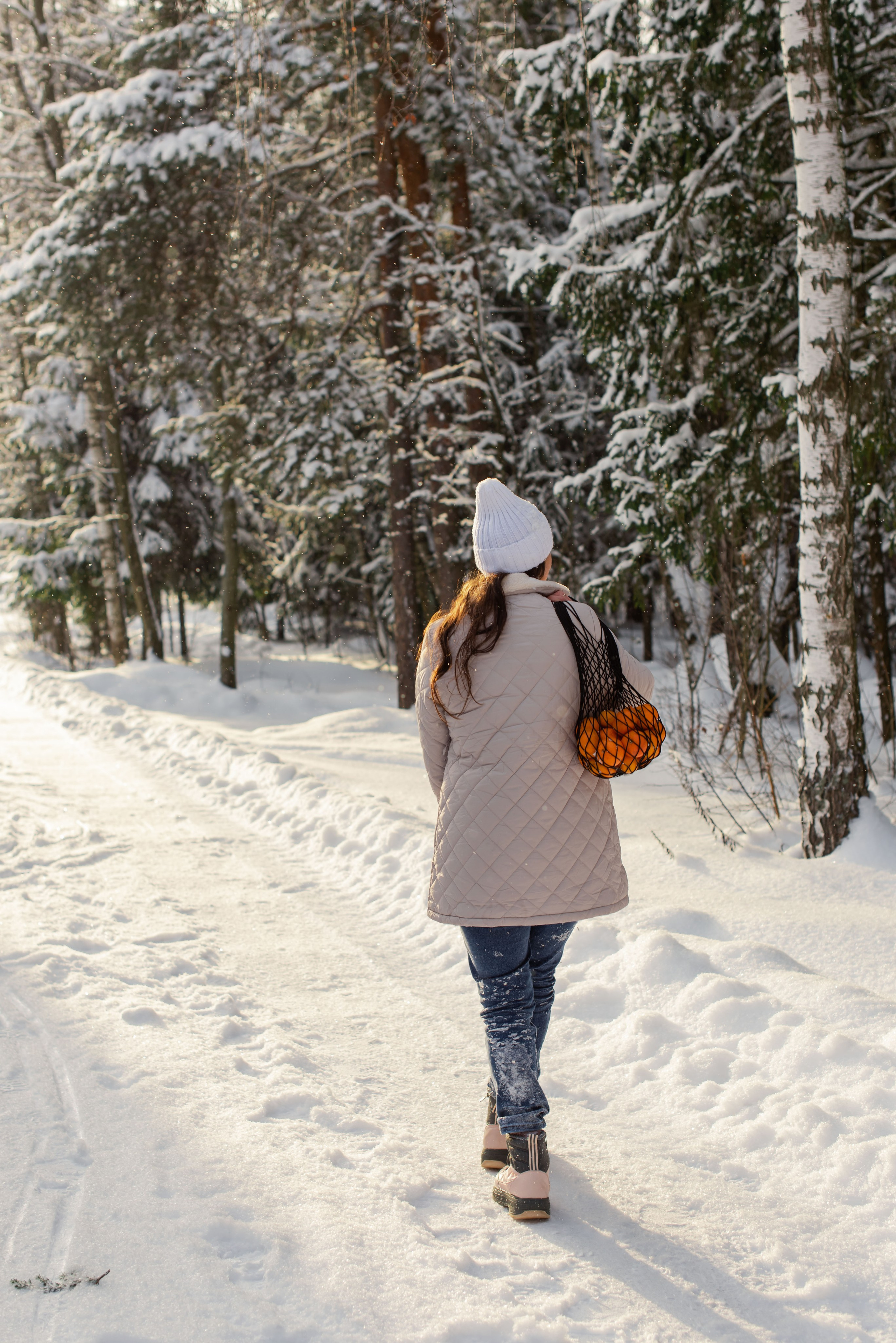 Девушка со сеткой мандарин — кадр на фоне заснеженного леса.