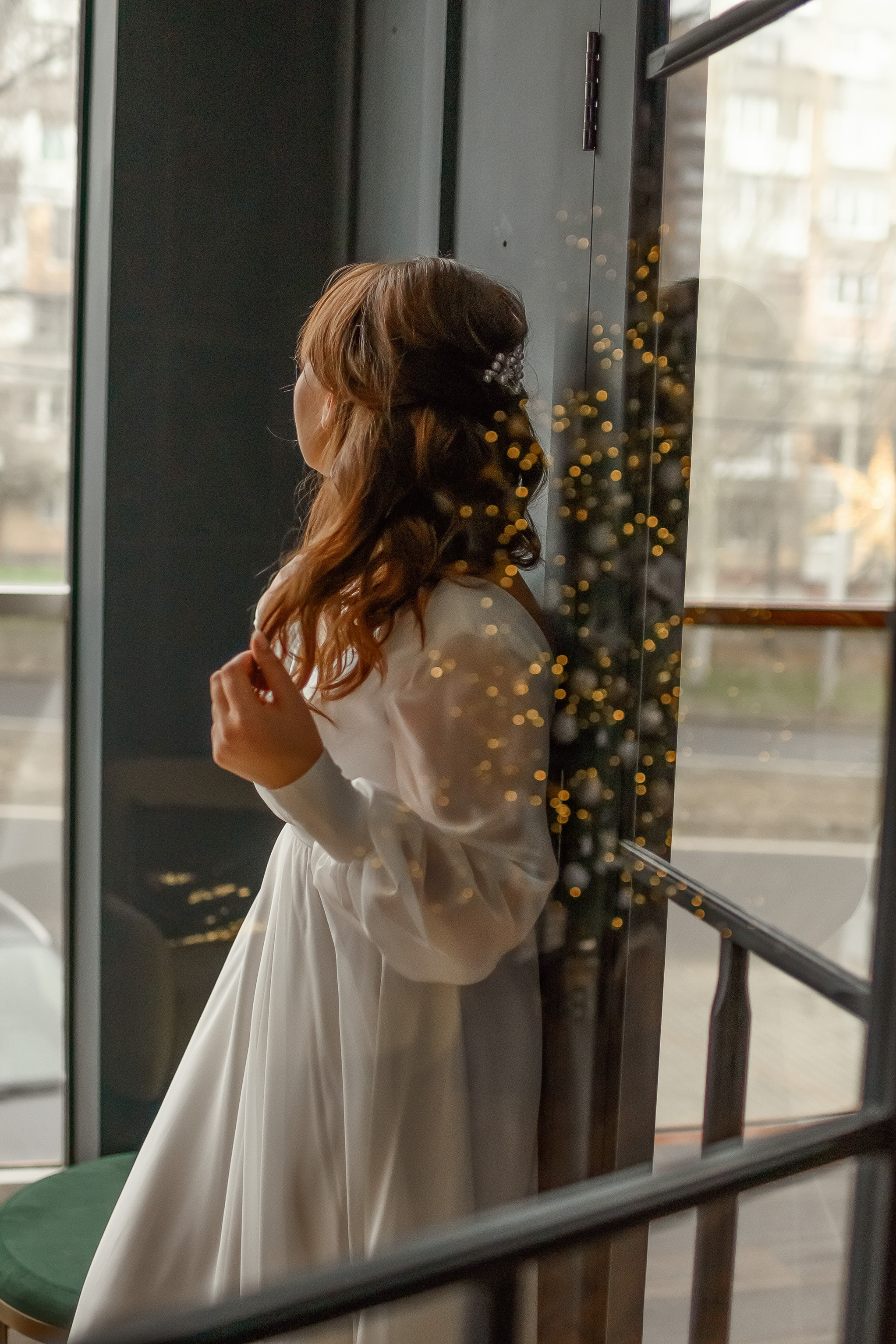 Девушка в свадебном платье смотрит в окно.