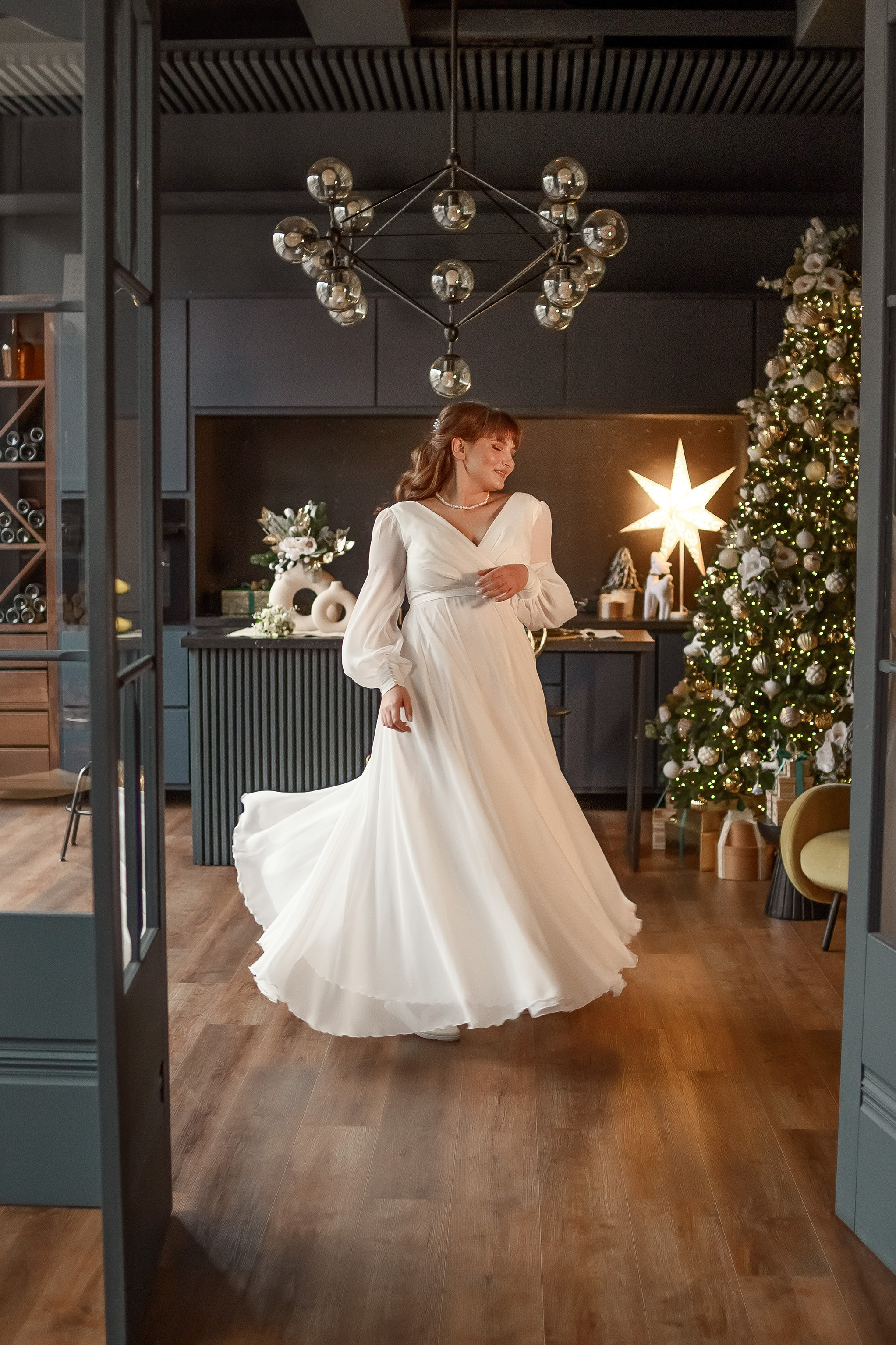 Невеста кружится в свадебном длинном платье в красивом зале.