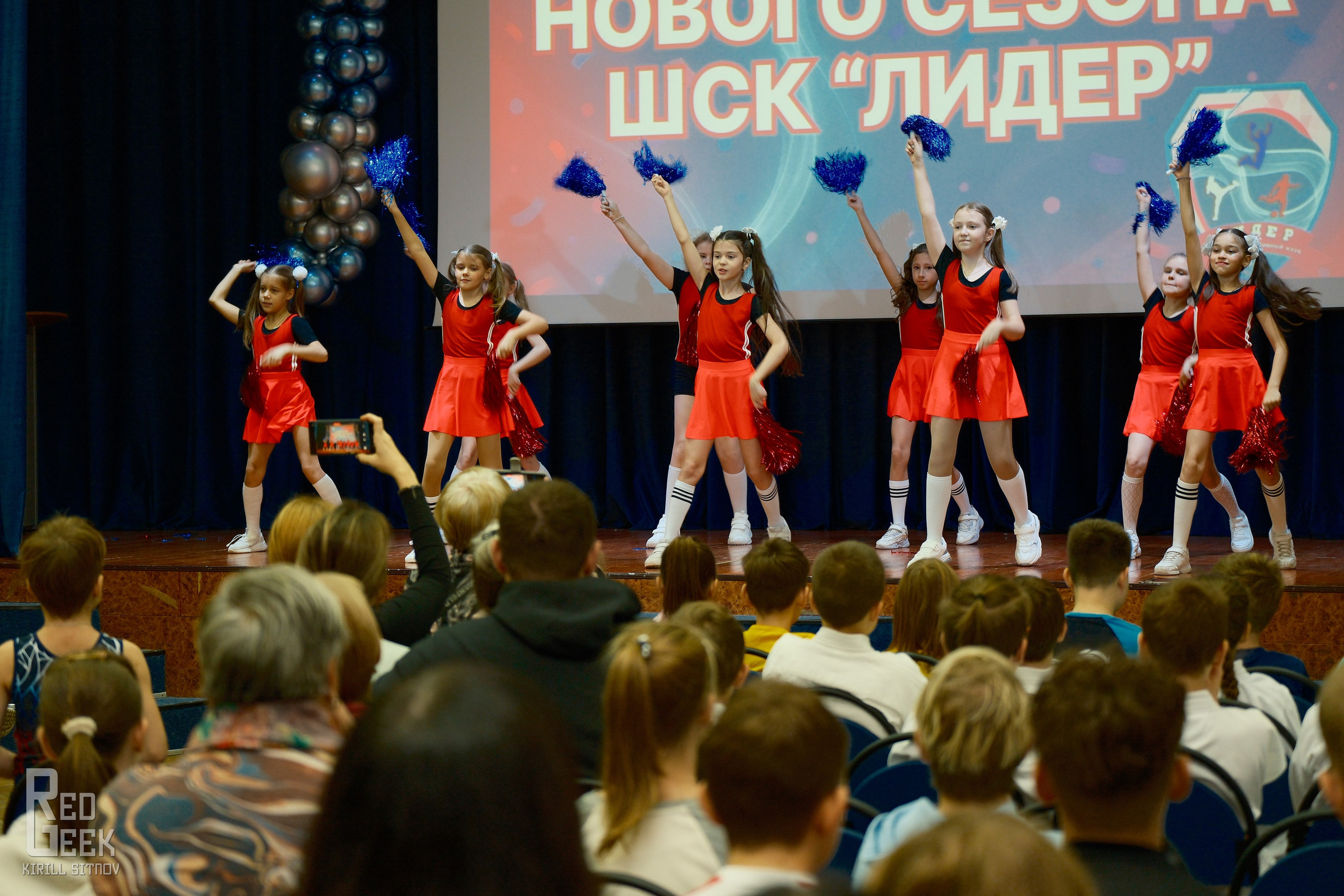 Школьные черлидерши в красных костюмах демонстрируют яркое выступление.
