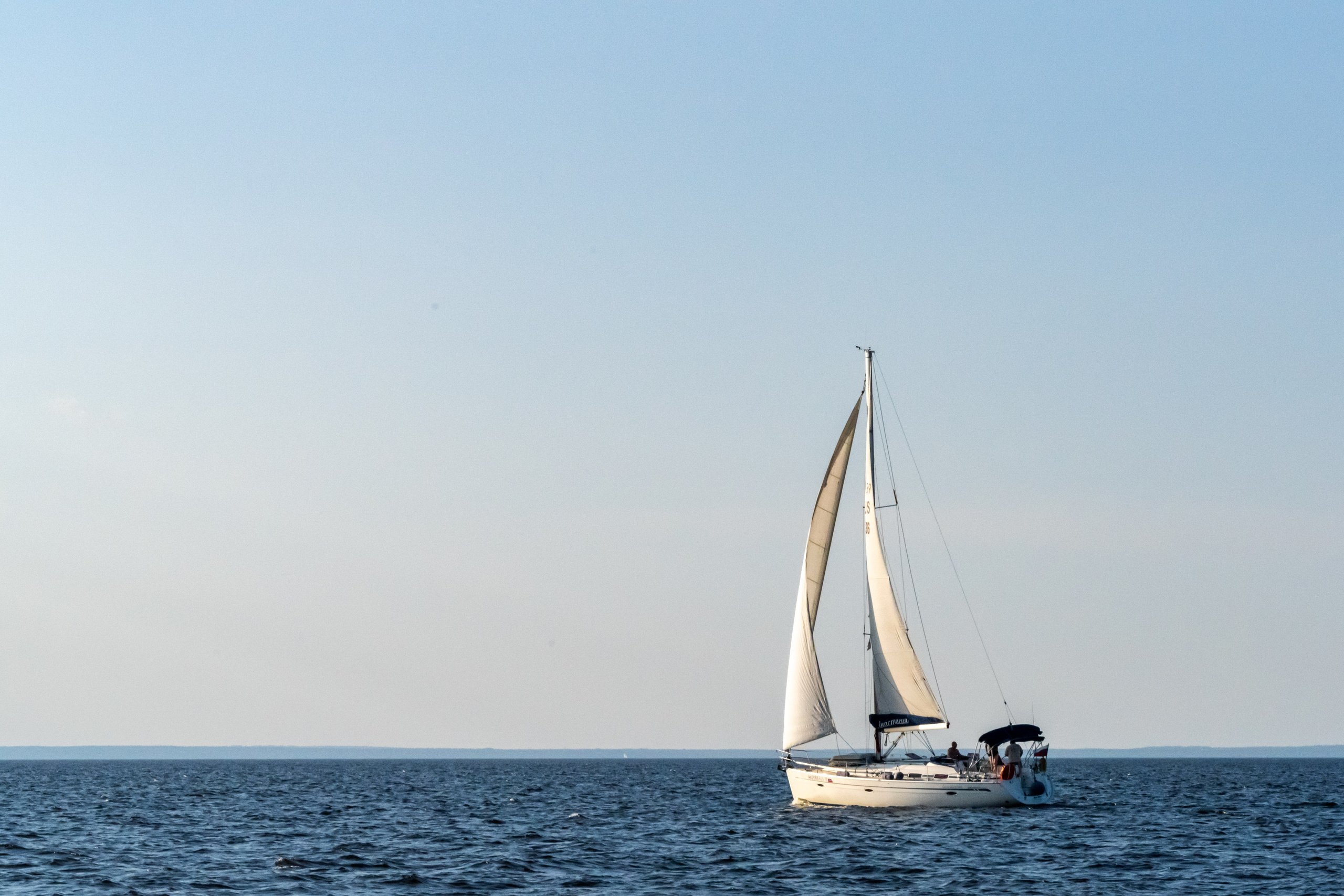 Яхта на воде на фоне голубого неба и синей воды