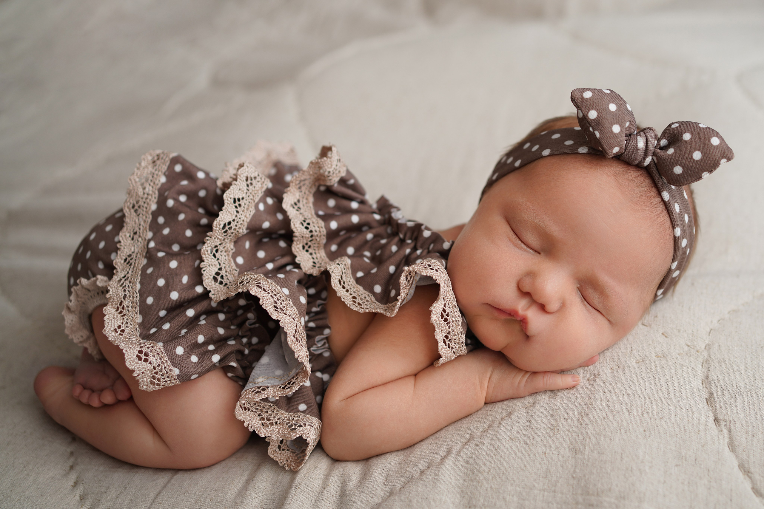 На фото новорожденная малышка, которой 10 дней. На ней красивое платье и повязочка в горошек.