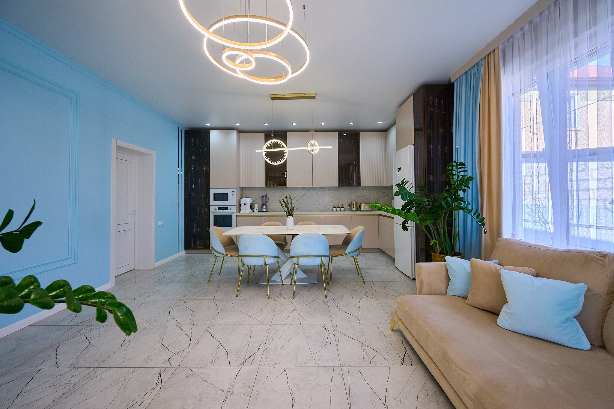 кухня голубые стены бежевый диван кухонный белый стол и белые стулья черно белые шкафы 