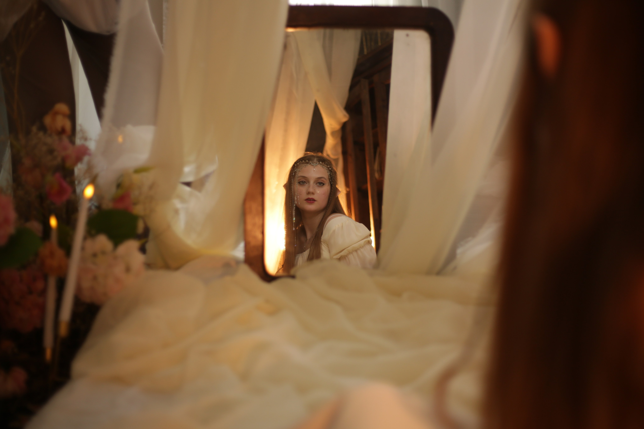 Тематическая фотосессия в Перми: девушка в белом платье с ушками и головным убором, сидит на кровати под полупрозрачным балдахином