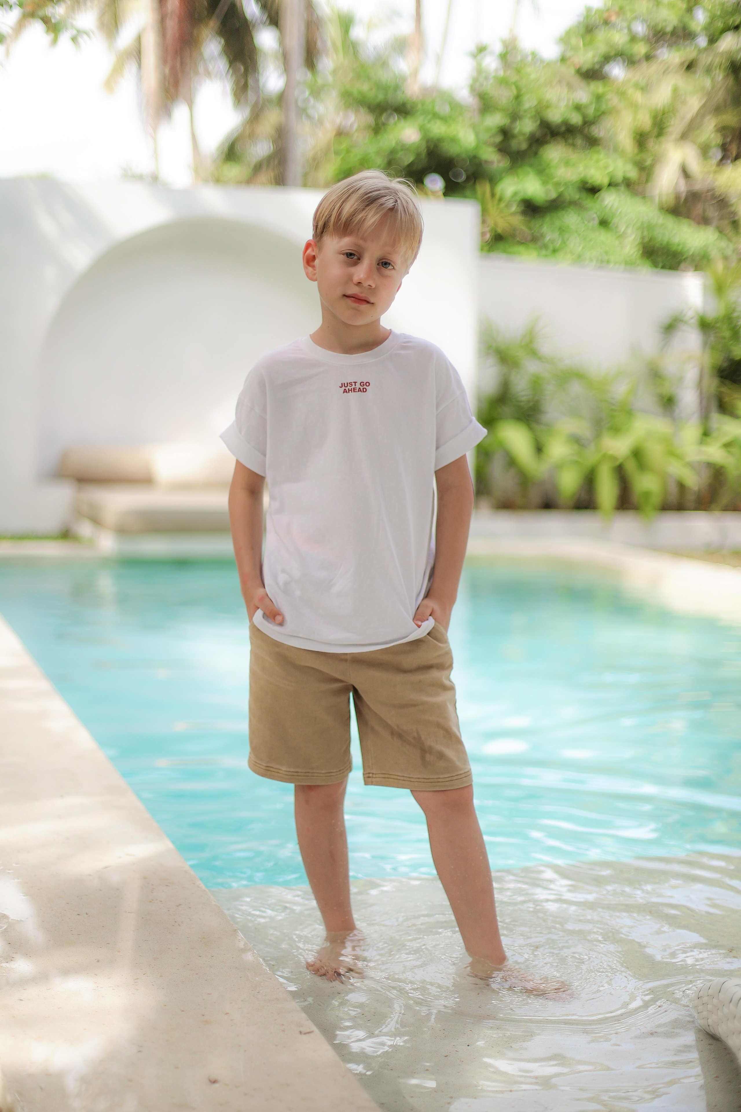 «Сын смеётся у воды: золотые блики на поверхности бассейна»