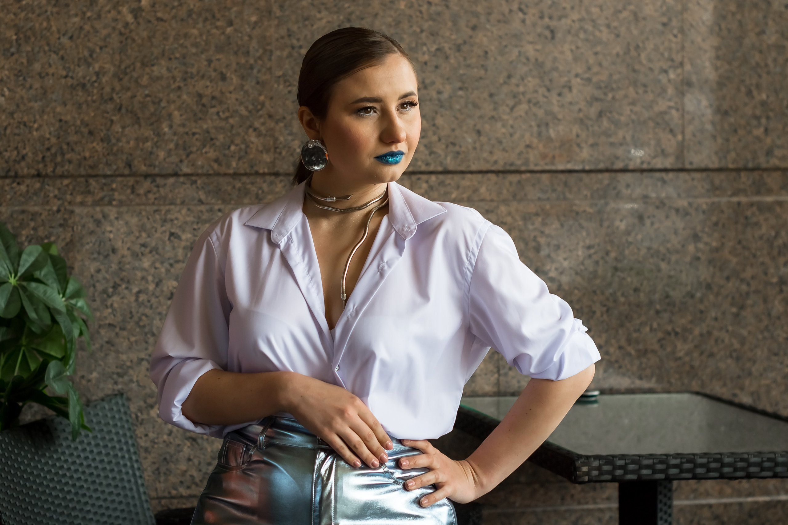 На фото девушка в белой рубашке сидит и смотрит вдаль.