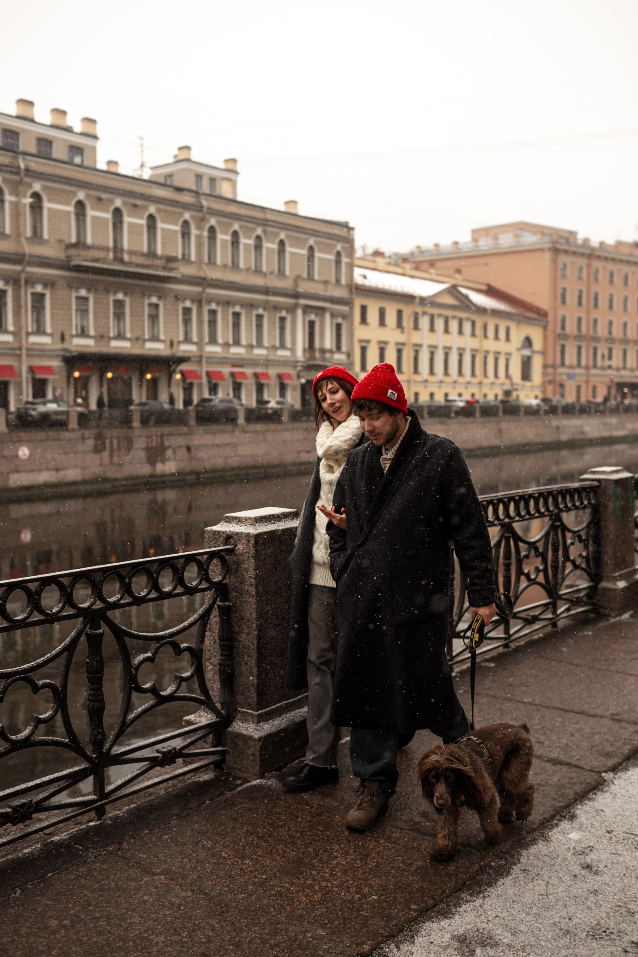 Влюбленные на фотосессии love story гуляют с собакой по набережной.