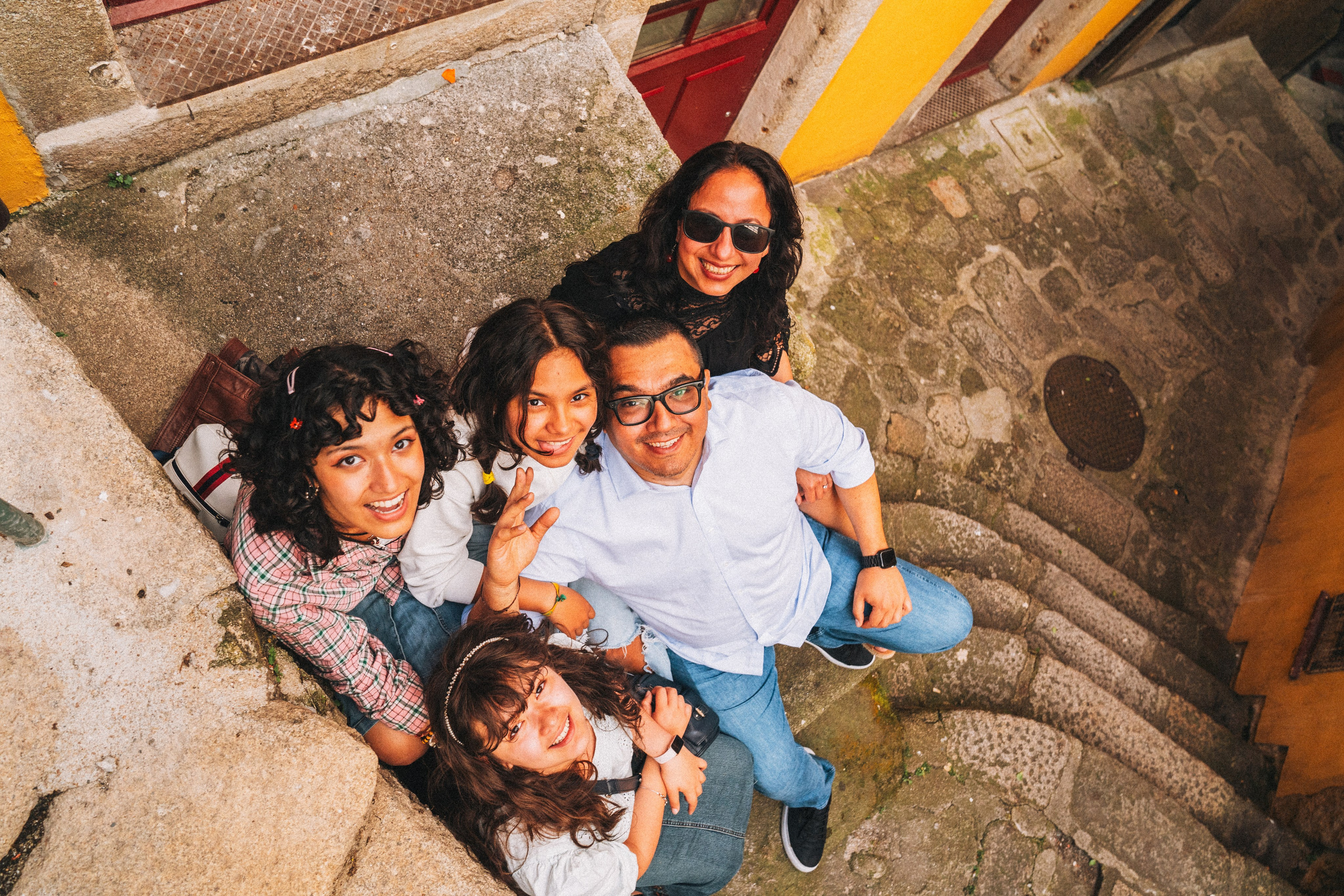 Группа людей семья влюбленные гуляет по живописной узкой улочке в Португалии, окружённой старыми домами и зеленью.