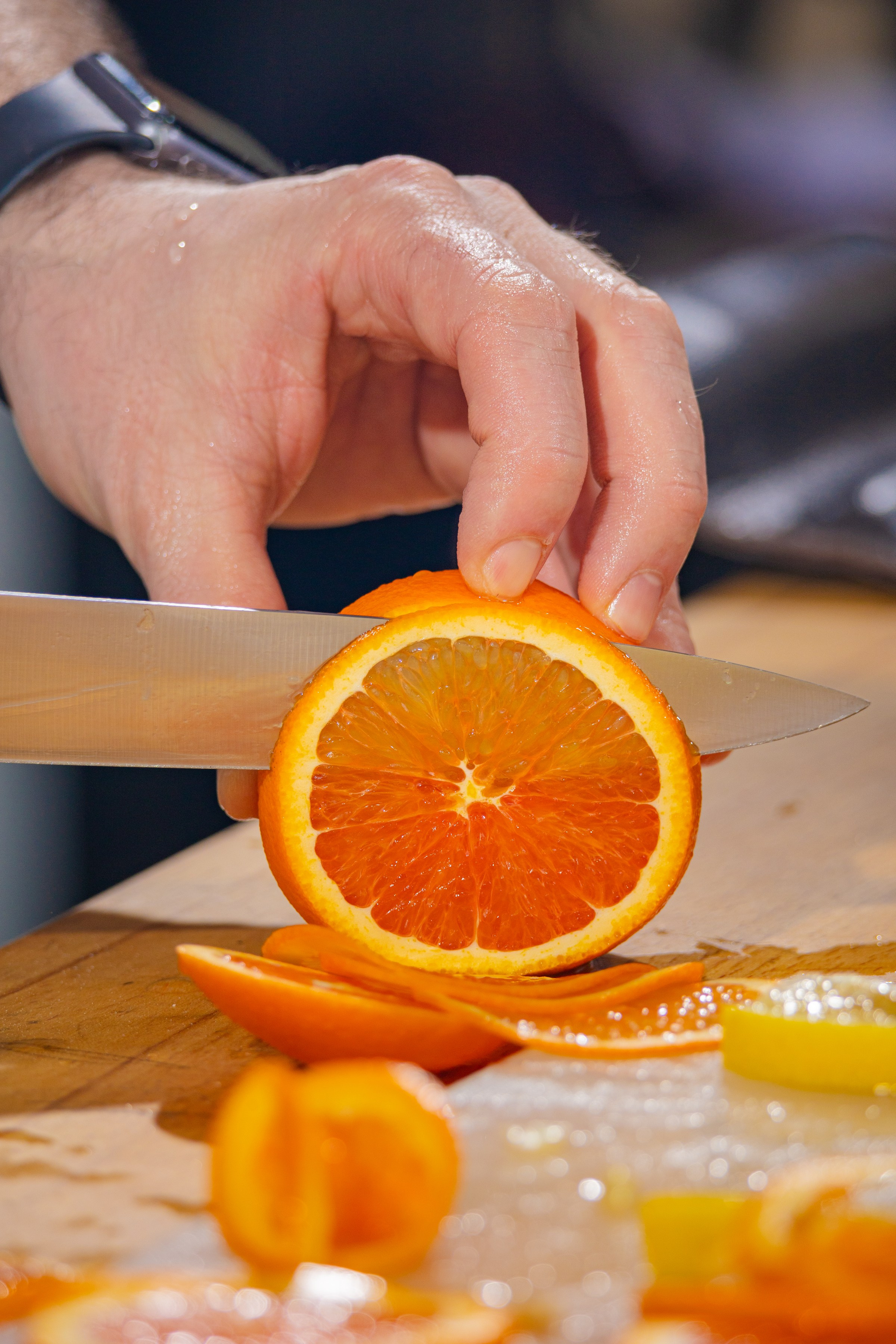Кулинарная студия артишок момент нарезания апельсина близко сфотографировал с ножом в руке