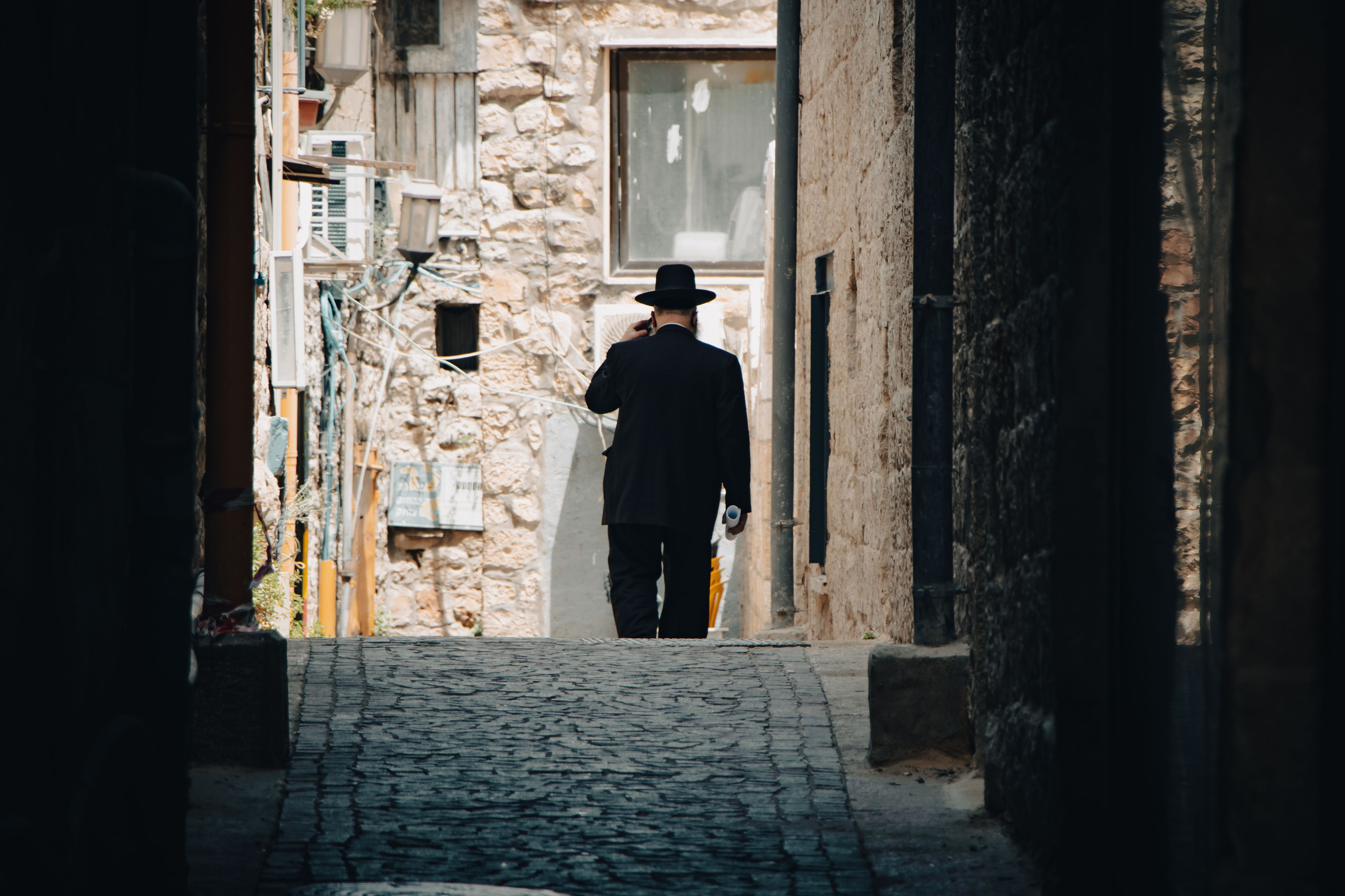 Еврей в шляпе гуляющий по улицам Иерусалима