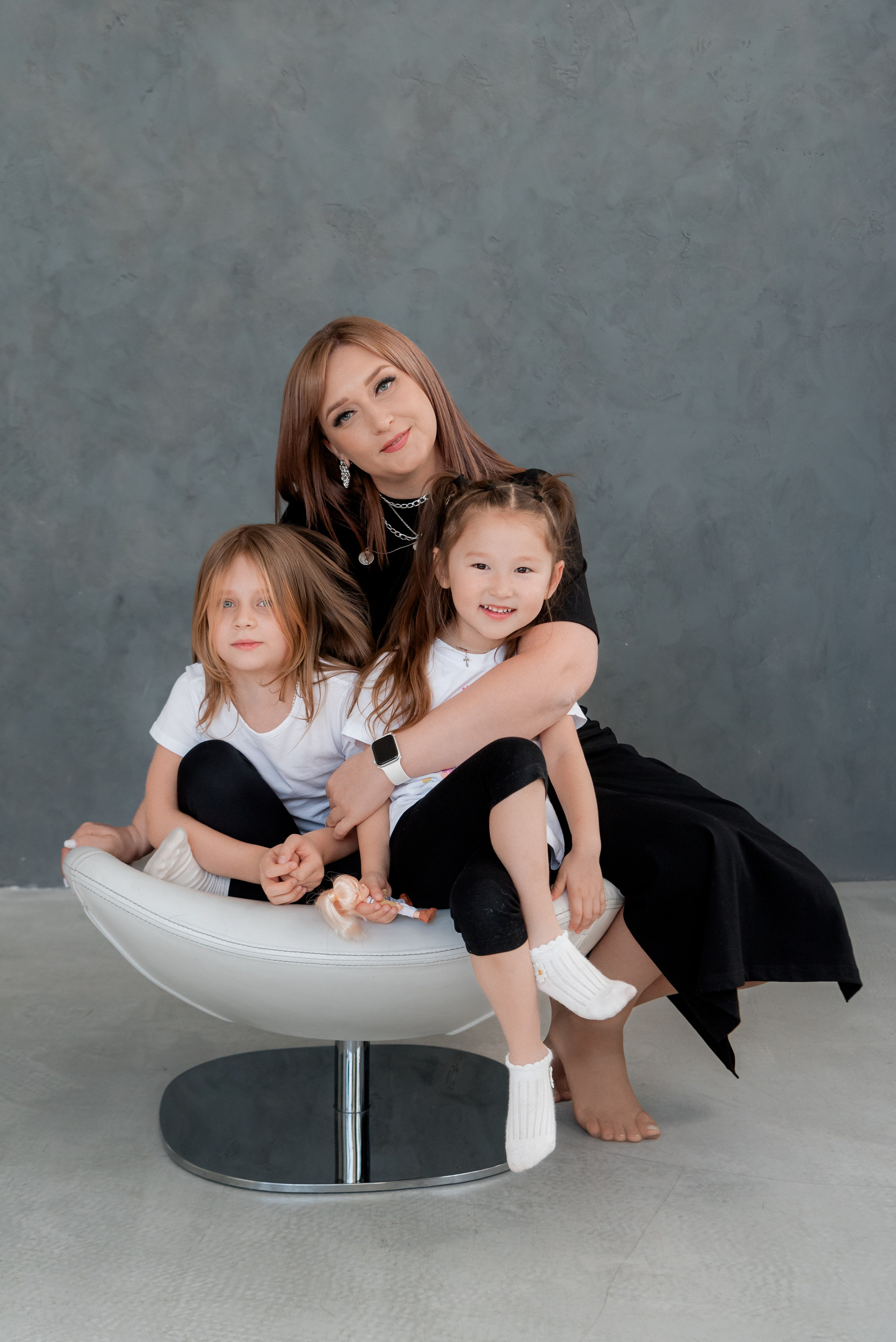 Мама обнимает дочек в студии на кресле
