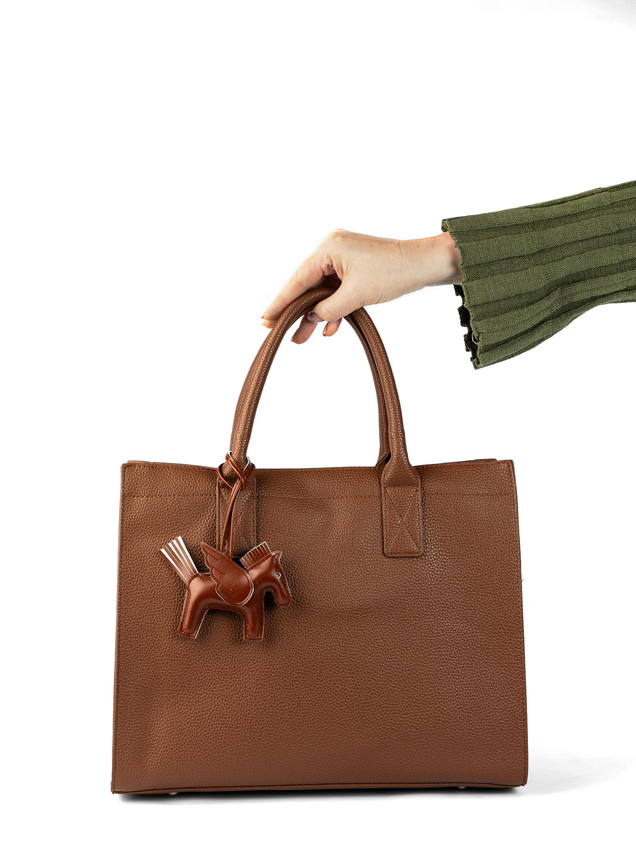 коричневая сумка в руках модели на белом фоне