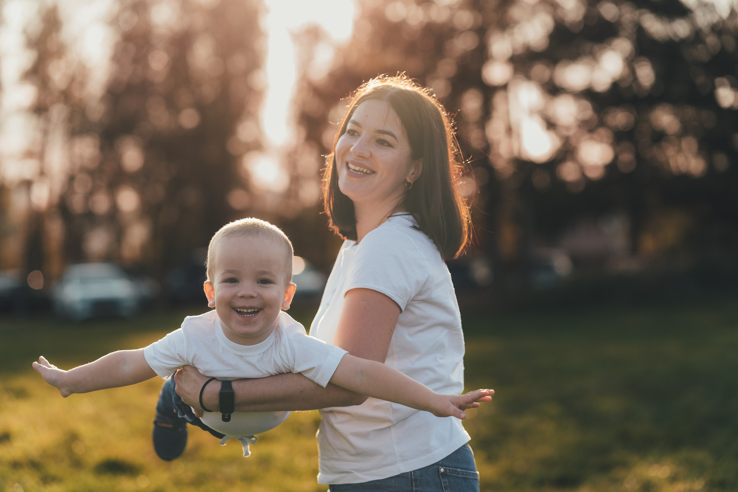 Сын с мамой в лучах закатного солнца, мама катает сына на руках