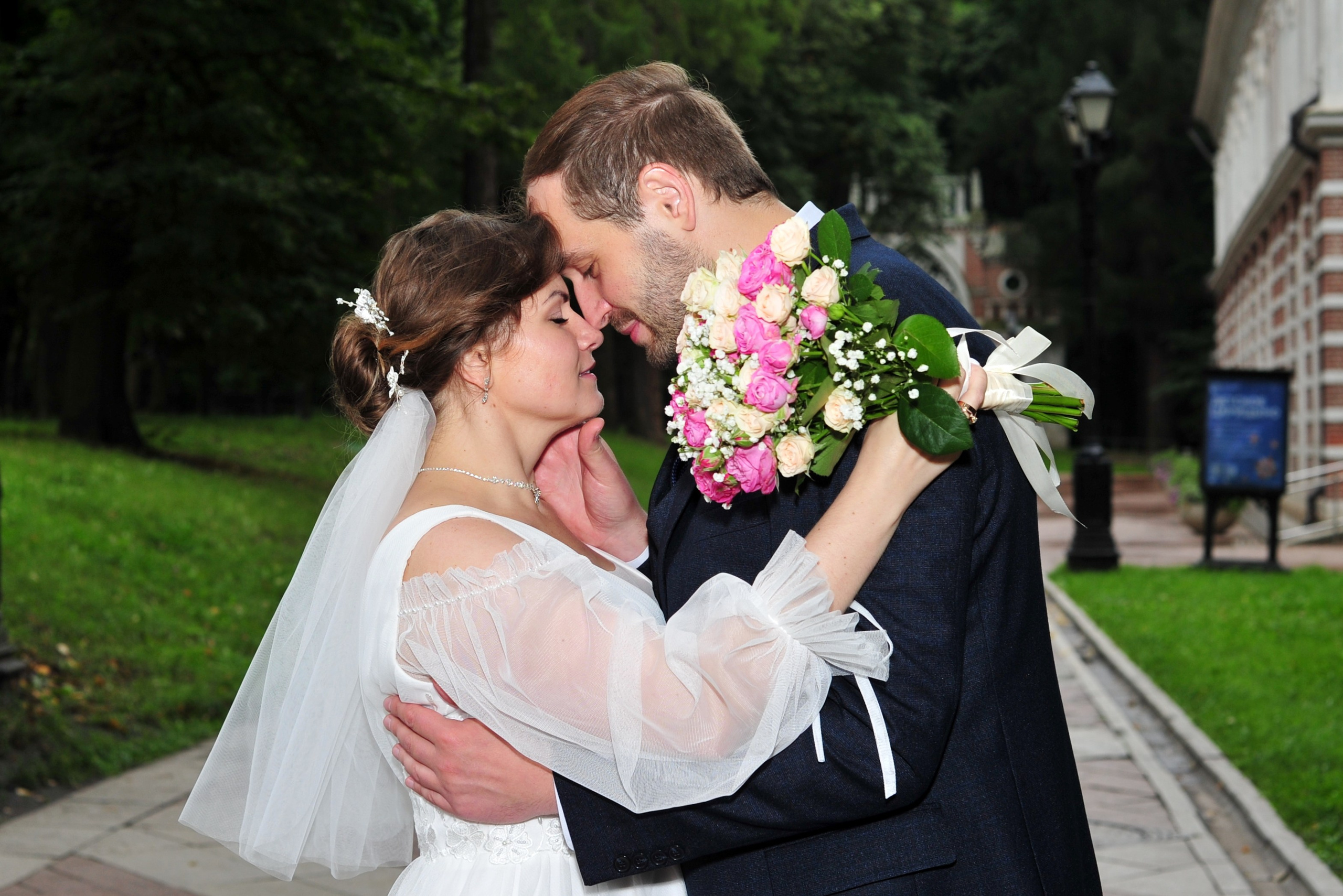 Свадьба в Царицыно пасмурным летним днем, новобрачные обнимаются на фоне темного парка перед грозой 