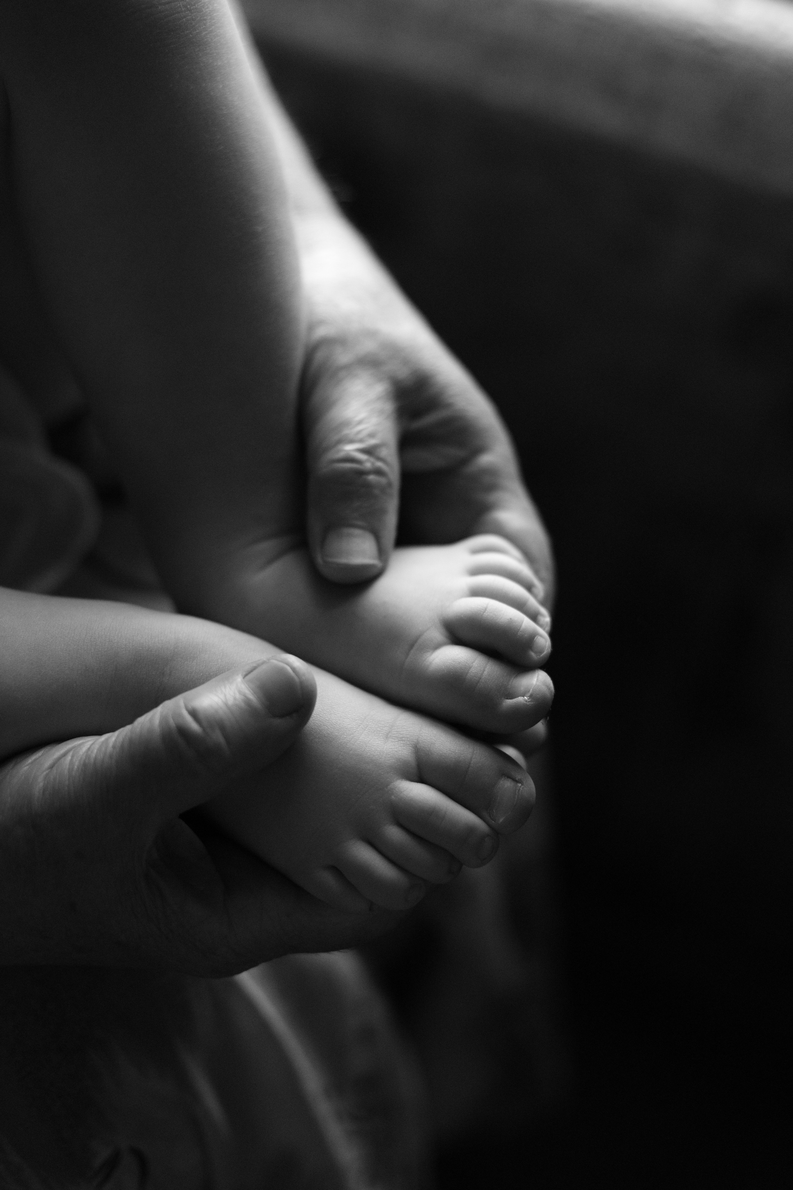 Бабушка держит босые ножки ребенка в своих руках крупным планом у окна