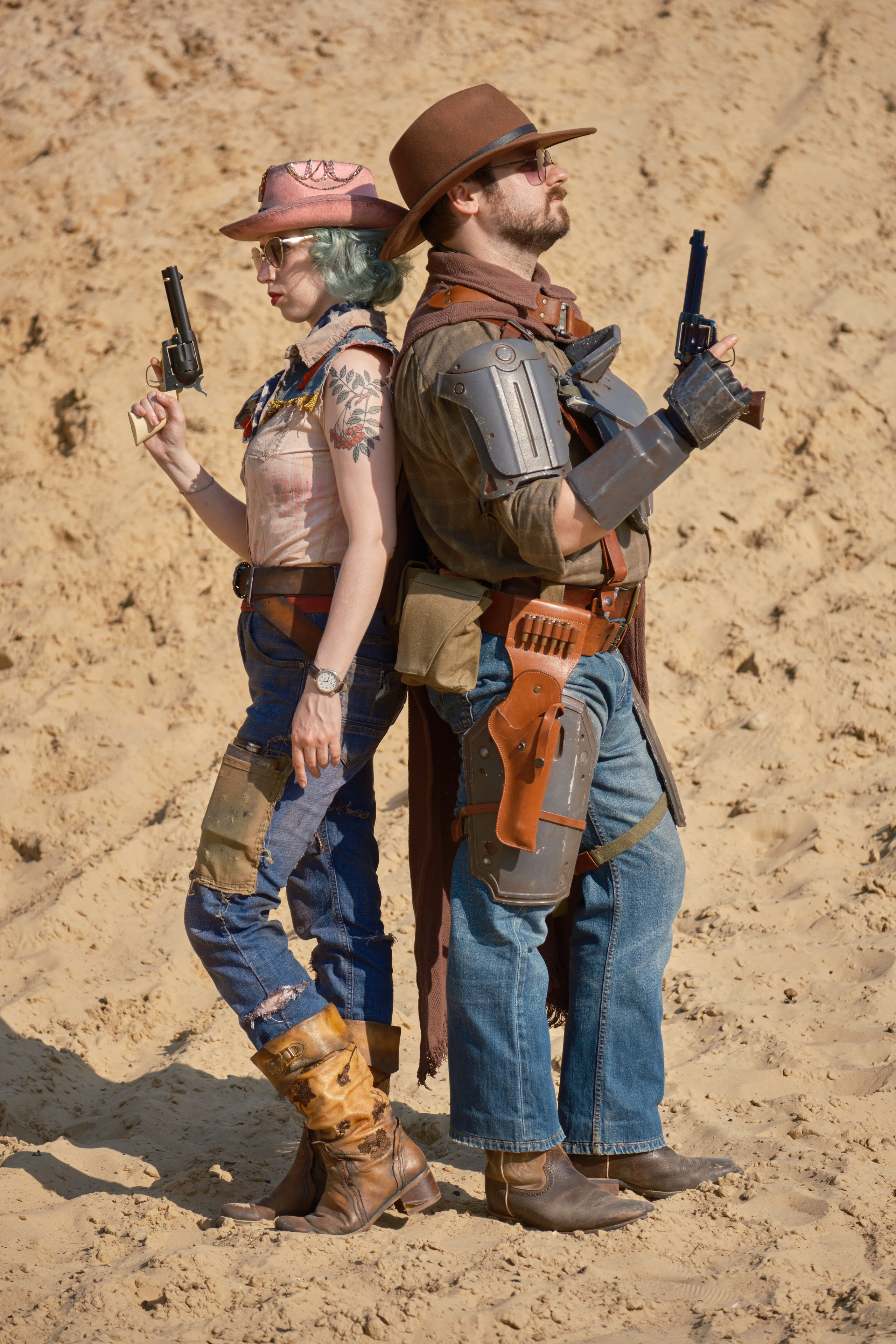 Мужчина и девушка в ковбойских шляпах и револьверами стоят спина к спине