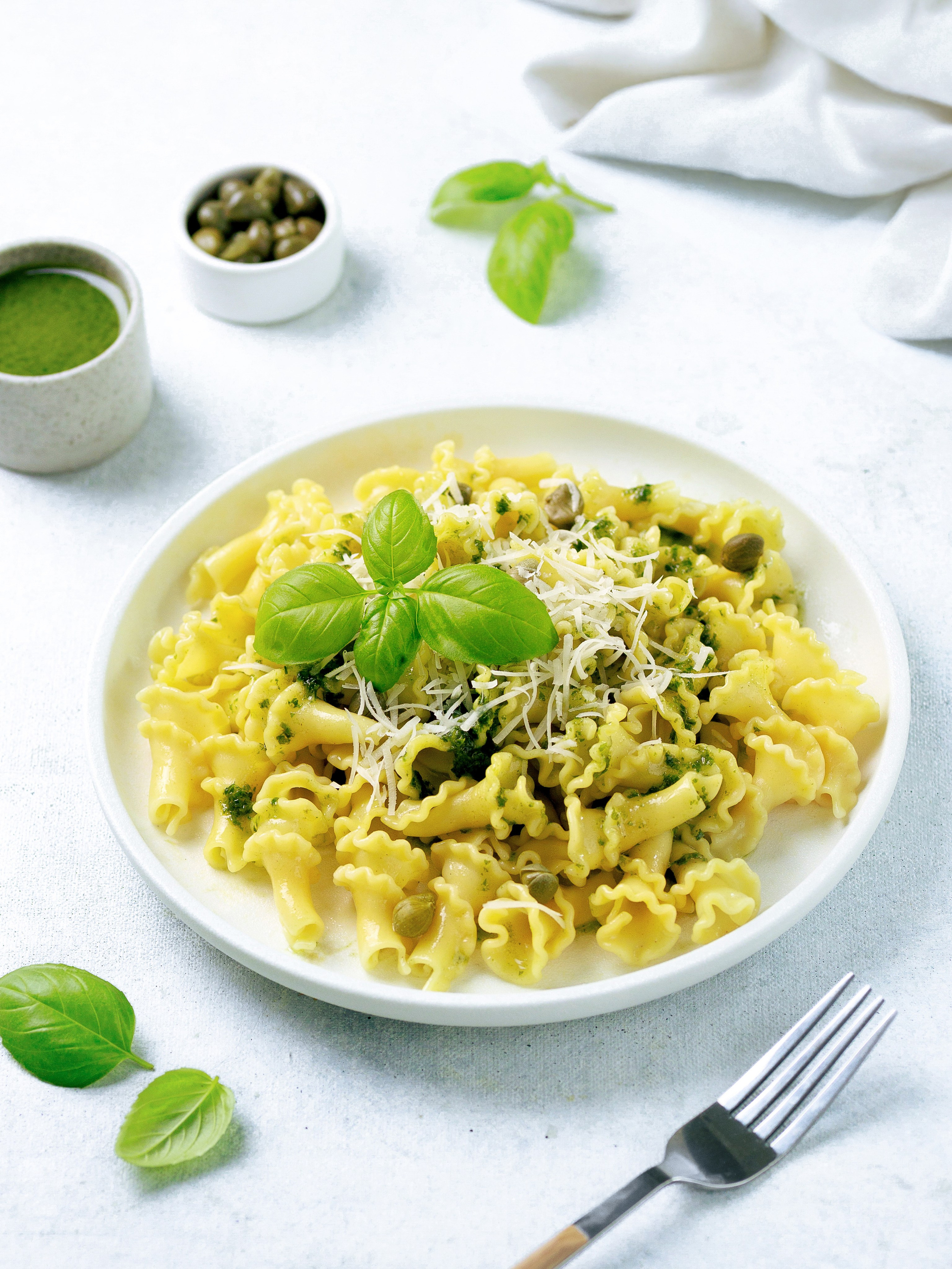 макароны с сыром и с каперсами на светлом фоне, фудстайлинг блюда.