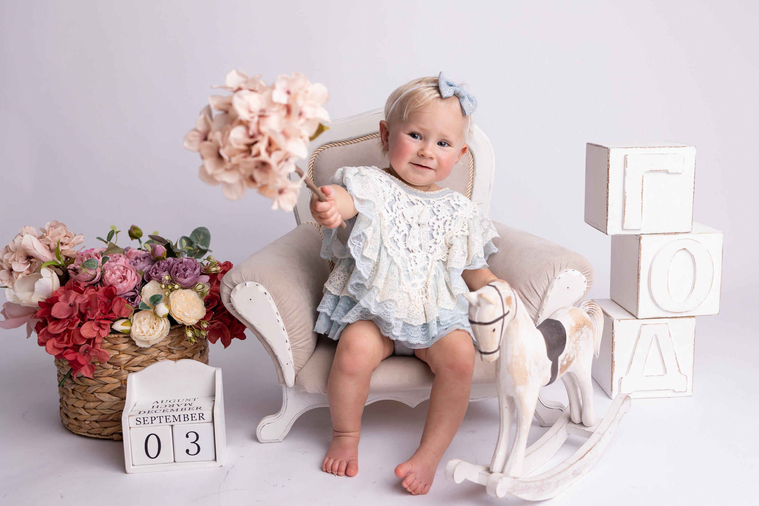 Малыш с цветком позирует на стуле рядом с календарем, указывающим на 3 сентября.