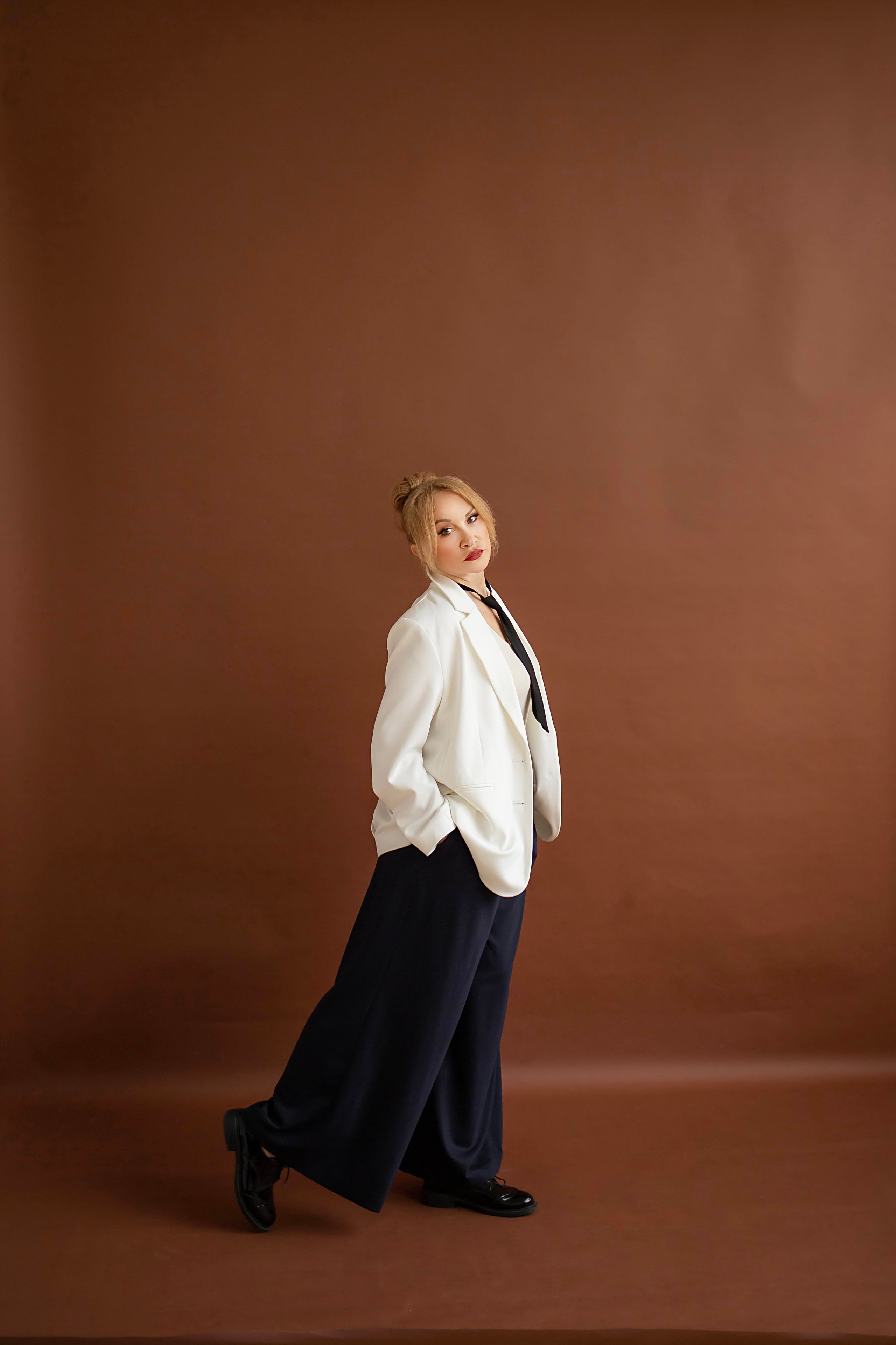 Нежный женский портрет в студии с естественным светом от окна, постельный коричневый фон