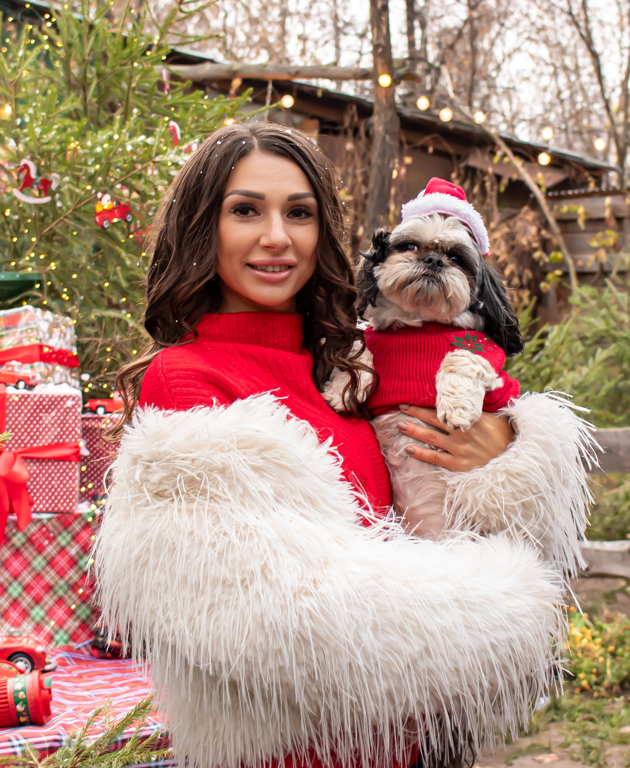 Женщина в белой шубе и красных брюках идёт по новогодней улице среди огоньков, фотограф Карасёва Елена