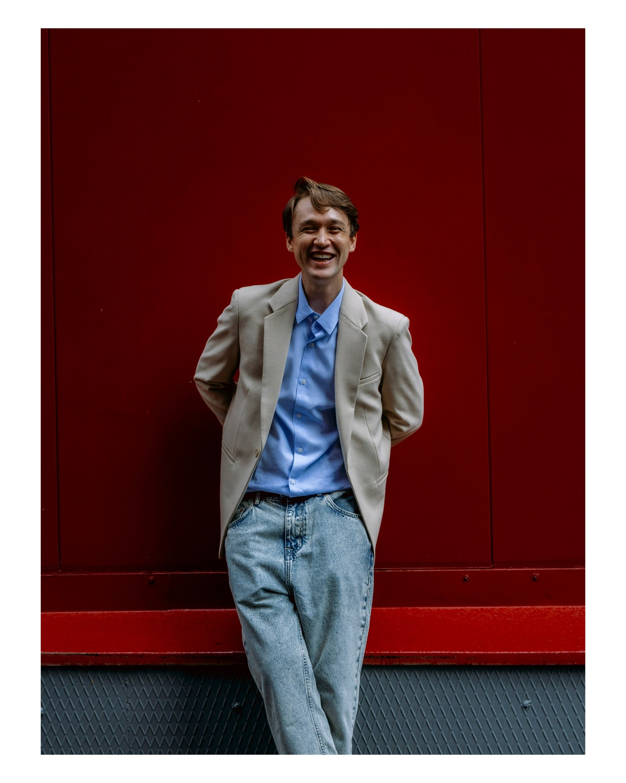 парень на красном фоне смеется