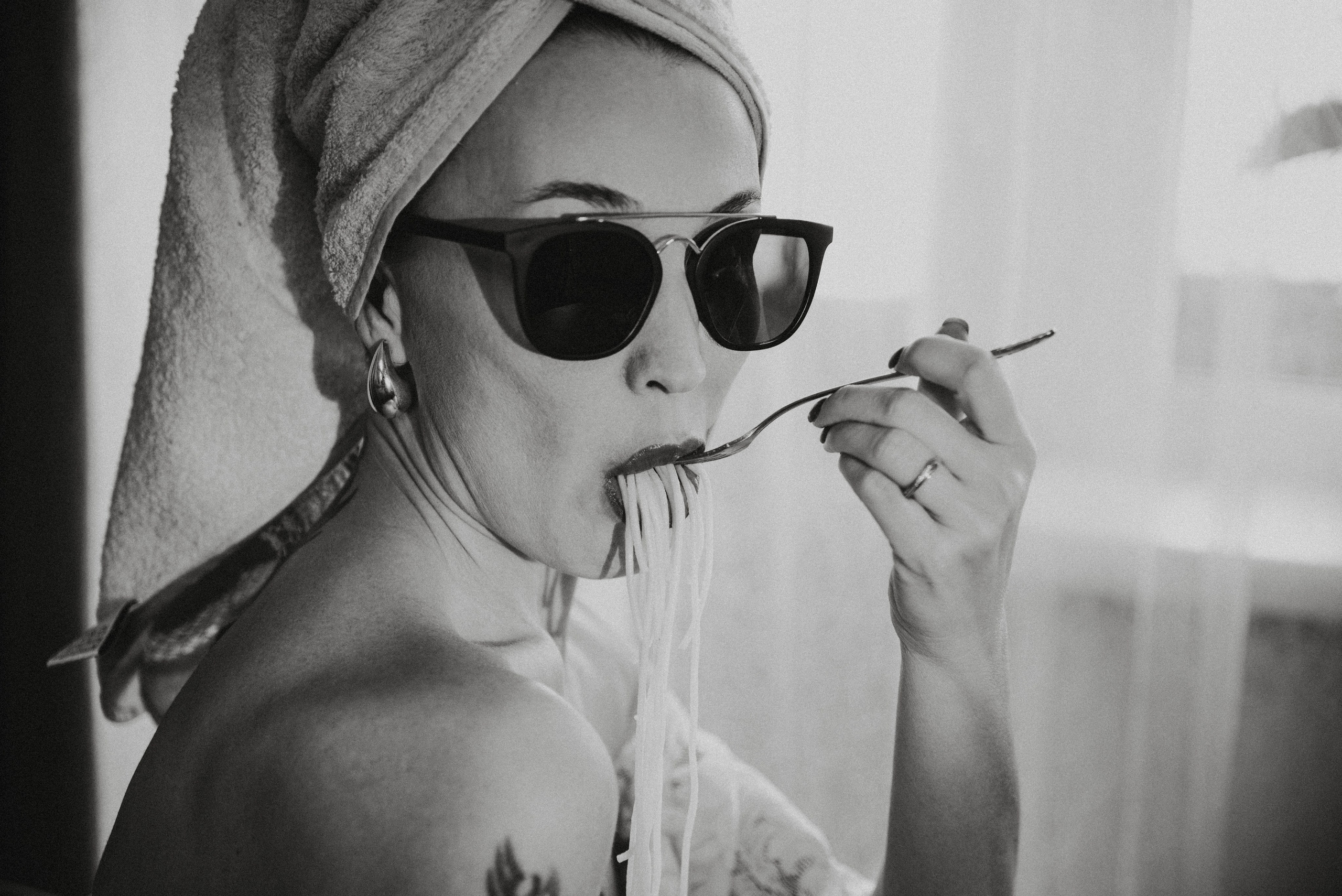 Девушка в полотенце на голове и солнцезащитных очках ест спагетти