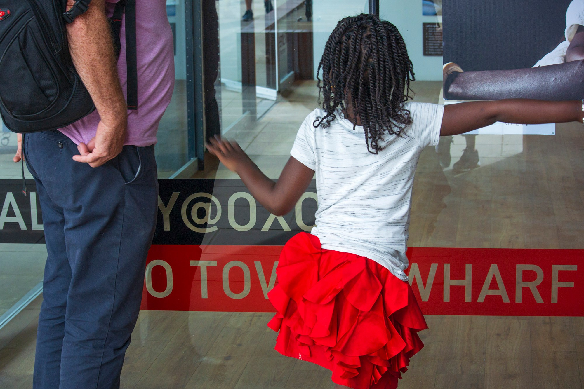 Мужчина и девочка с дредами стоят у стеклянной витрины с надписью «ALLEY OOP TOWER WHARF»