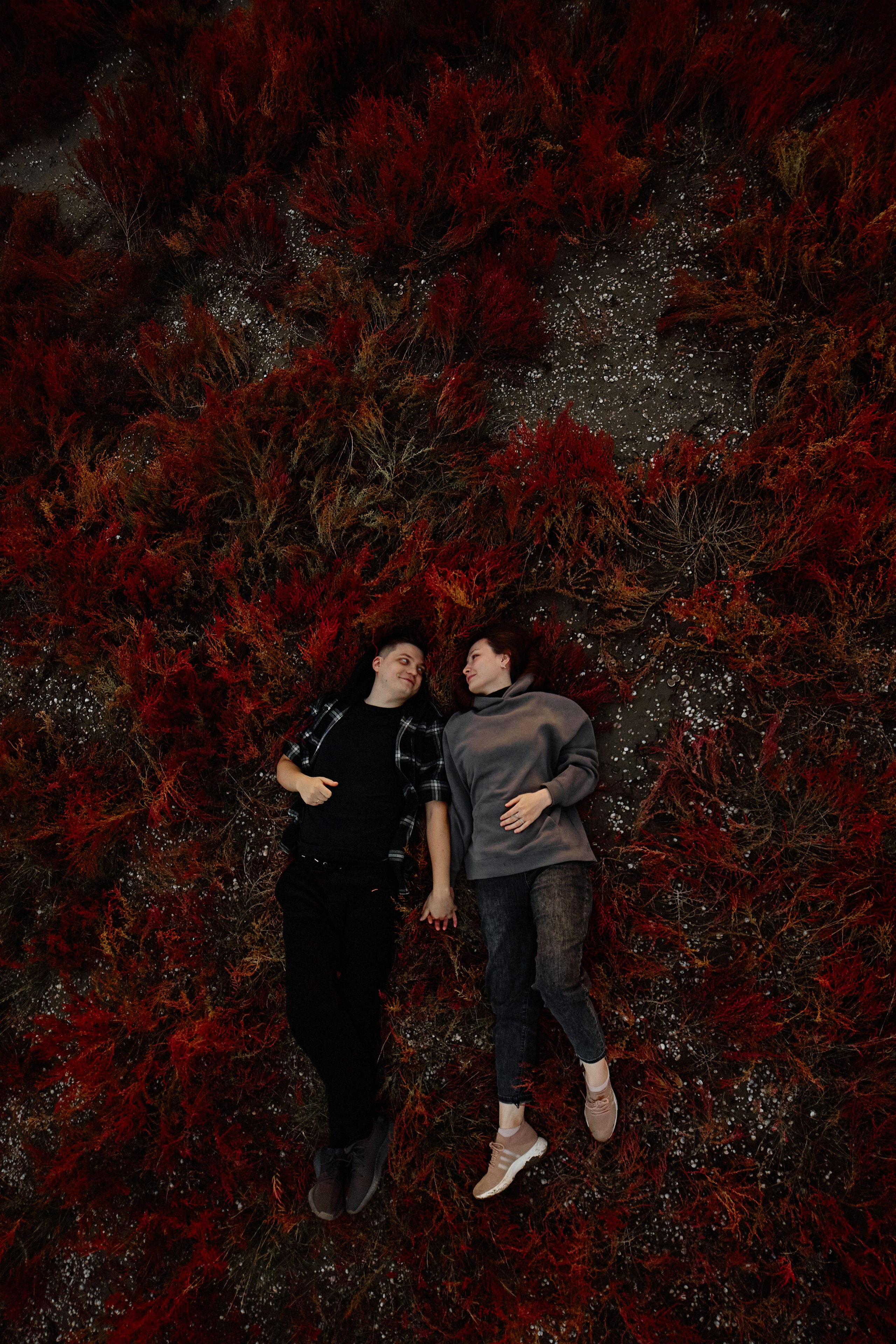 Пара лежит на красном солеросе на лав стори фотосессии в Анапе