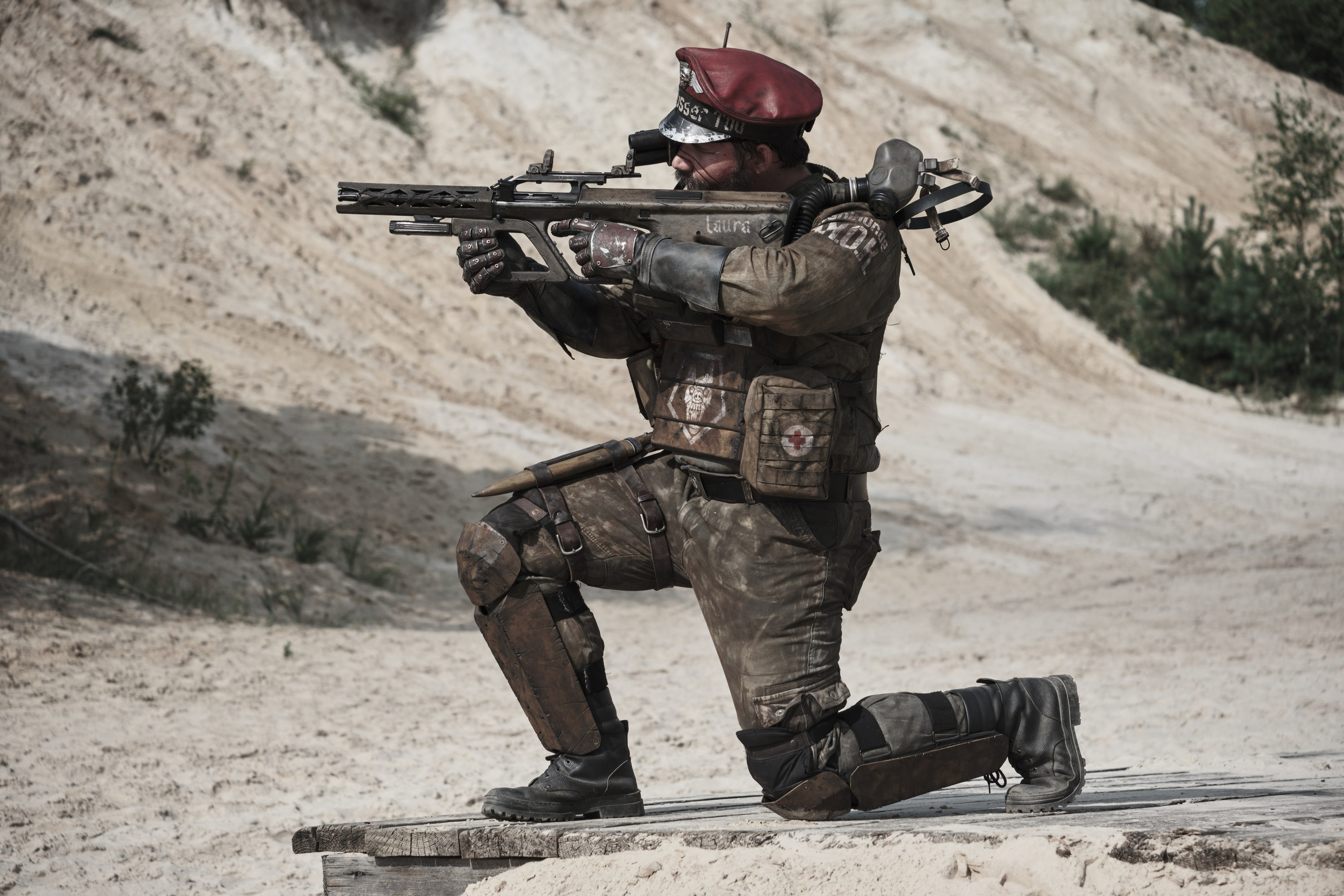 Мужчина в боевом костюме целиться из автомата в стиле пост апокалипсис