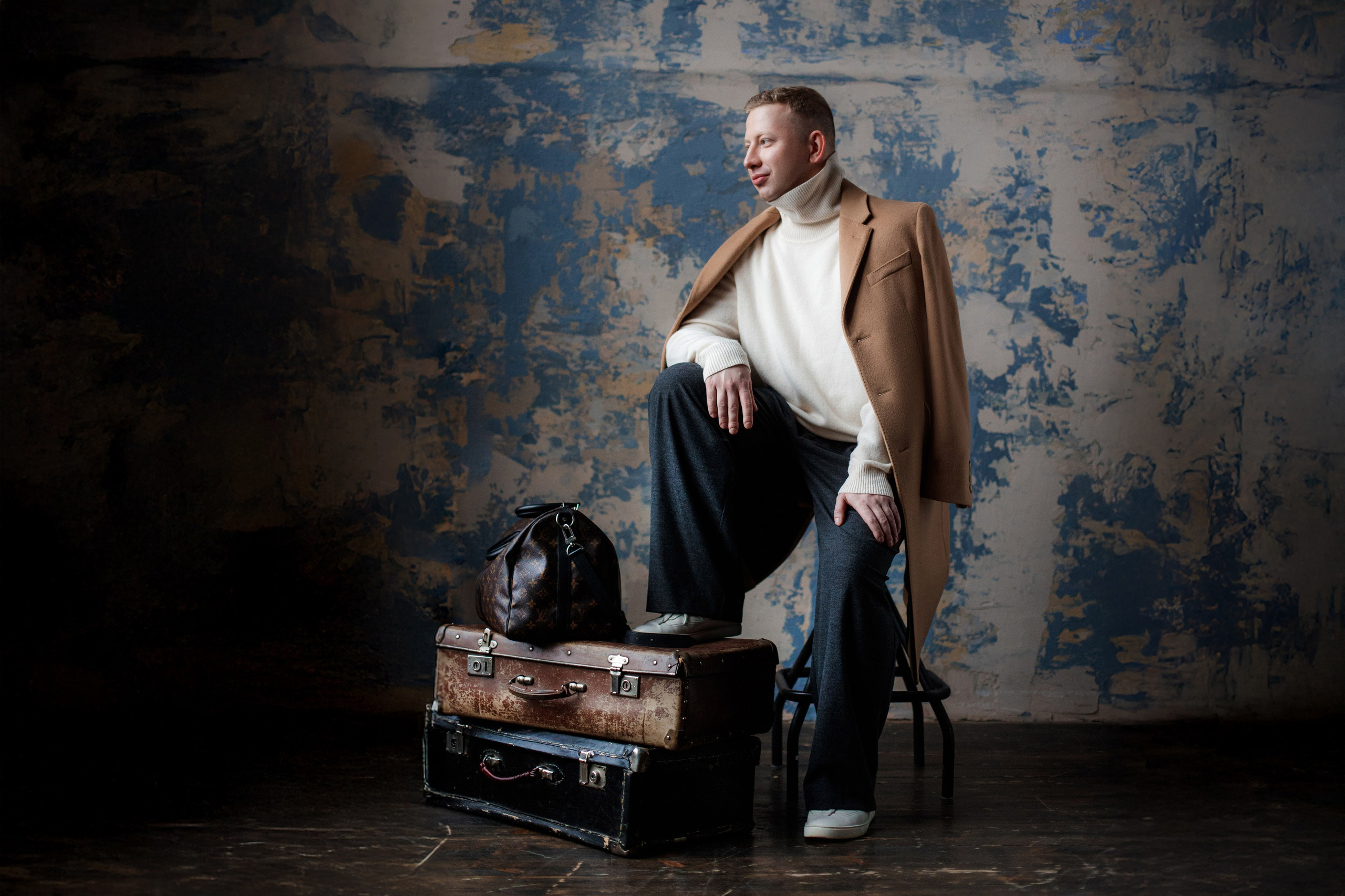 Мужчина в бежевом пальто на винтажных чемоданах, атмосферная студийная съемка — портретный фотограф Галина Скорик.